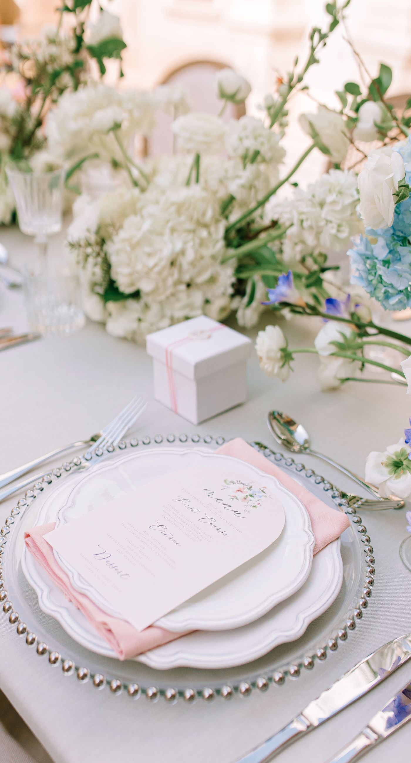 Alysia & Fraunk - Amidst the backdrop of a weathered, pale peach facade with antique windows, an enchanting scene unfolds. The romantic embrace of a couple is tenderly framed by a symphony of pastel-hued florals—soft pinks, gentle blues, and creamy whites—exuding timeless elegance. The delicate wild arrangements accentuate the ethereal beauty of the bridal dress, while the muted tones of the aged architecture blend seamlessly with the lush, garden-like display. This harmonious composition captures the essence of rustic romance, showcasing the florist's ability to weave nature's hues into a visual poem of love. - Photo 3