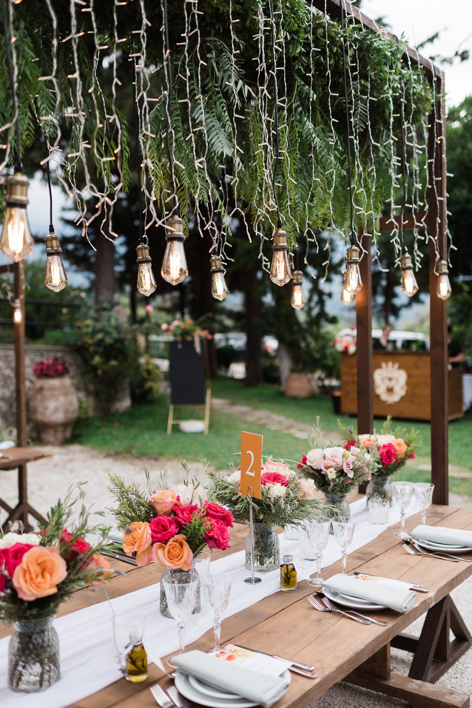 Amber & Thadrick - This enchanting scene captures a romantic celebration framed by lush greenery and a vibrant floral display, making it an ideal centerpiece for a florist's portfolio. The couple, adorned in elegant attire with delicate lace and soft hues, stand beneath a cascade of vivid pink and peach blooms that breathe life into the composition. The backdrop of verdant foliage provides a serene contrast, enhancing the vibrant florals and complementing the joyous atmosphere. This harmonious blend of natural beauty and crafted elegance showcases the florist's talent for creating breathtaking, heartwarming settings. - Photo 4