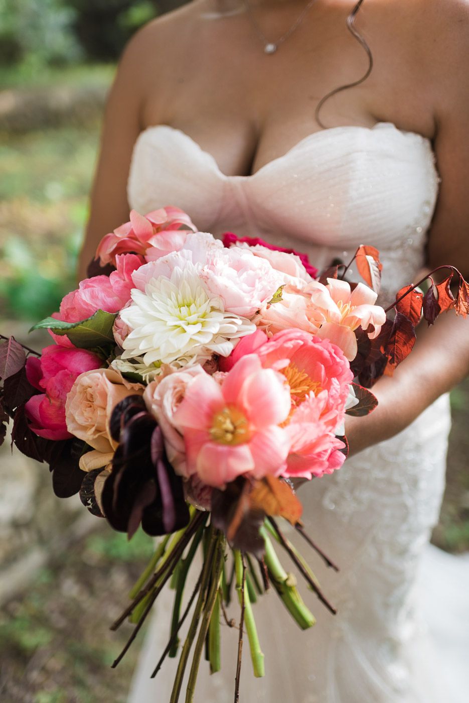 Amber & Thadrick - This enchanting scene captures a romantic celebration framed by lush greenery and a vibrant floral display, making it an ideal centerpiece for a florist's portfolio. The couple, adorned in elegant attire with delicate lace and soft hues, stand beneath a cascade of vivid pink and peach blooms that breathe life into the composition. The backdrop of verdant foliage provides a serene contrast, enhancing the vibrant florals and complementing the joyous atmosphere. This harmonious blend of natural beauty and crafted elegance showcases the florist's talent for creating breathtaking, heartwarming settings. - Photo 7