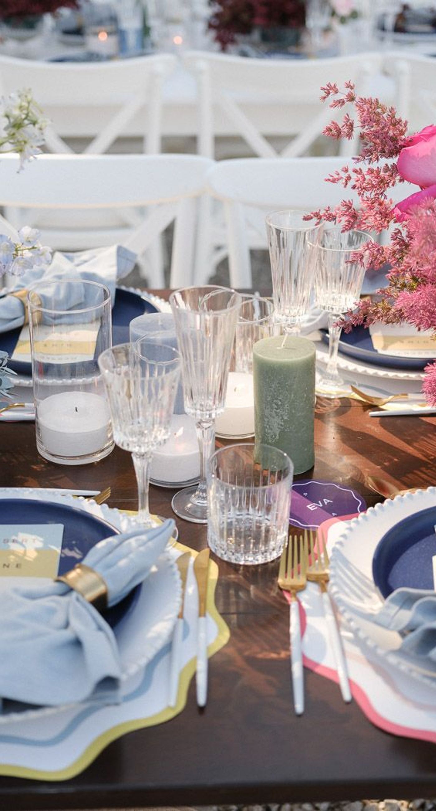 Amillia & Eriks - In this enchanting floral showcase, delicate blossoms cascade in a stunning array of pinks, purples, and deep reds, creating an ethereal backdrop for a moment of elegance and romance. The vibrant hues of the flowers stand out against the crisp white Mediterranean-style setting, evoking a sense of timeless beauty. Each bloom is meticulously arranged, showcasing the artistry and vision of bespoke floral design. The interplay of natural light dancing across the scene adds a touch of magic, ensuring that every detail invites admiration and adds to the harmonious, yet bold aesthetic. - Photo 4