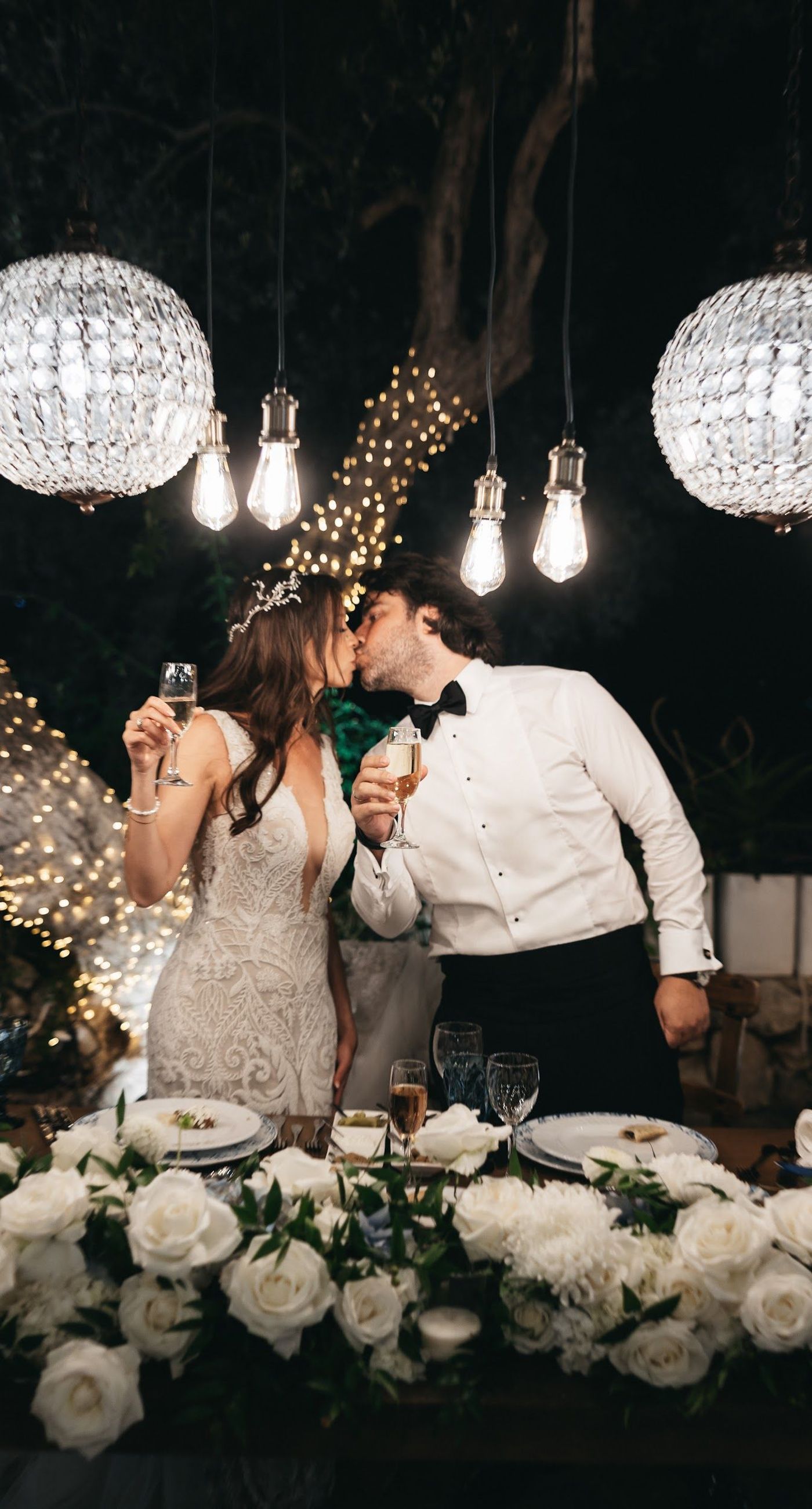 Andria & Alan - Bathed in the golden glow of a setting sun, this moment exudes an elegant blend of warmth and romance. The gentle hues of greenery and the soft embrace of light create a serene ambiance, perfectly framing the delicate embroidery of a bridal gown. The subtle interplay of shadow and light, with touches of white and green flowers, enhances the luxurious simplicity of the scene. This exquisite piece captures the essence of an enchanting outdoor celebration, where nature and elegance harmoniously unite, offering a timeless backdrop for cherished memories. - Photo 11