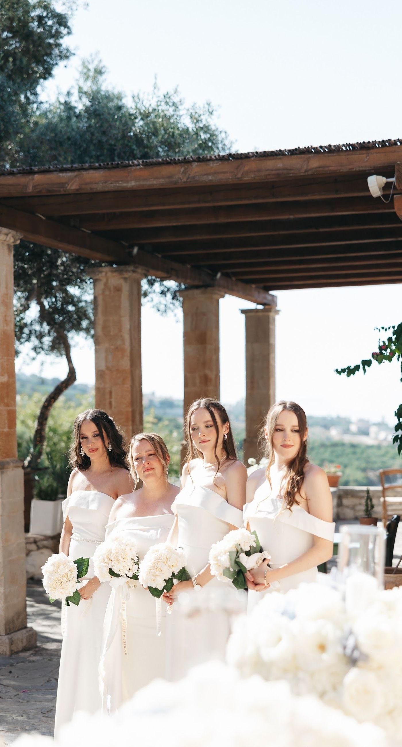 Andria & Alan - Bathed in the golden glow of a setting sun, this moment exudes an elegant blend of warmth and romance. The gentle hues of greenery and the soft embrace of light create a serene ambiance, perfectly framing the delicate embroidery of a bridal gown. The subtle interplay of shadow and light, with touches of white and green flowers, enhances the luxurious simplicity of the scene. This exquisite piece captures the essence of an enchanting outdoor celebration, where nature and elegance harmoniously unite, offering a timeless backdrop for cherished memories. - Photo 9