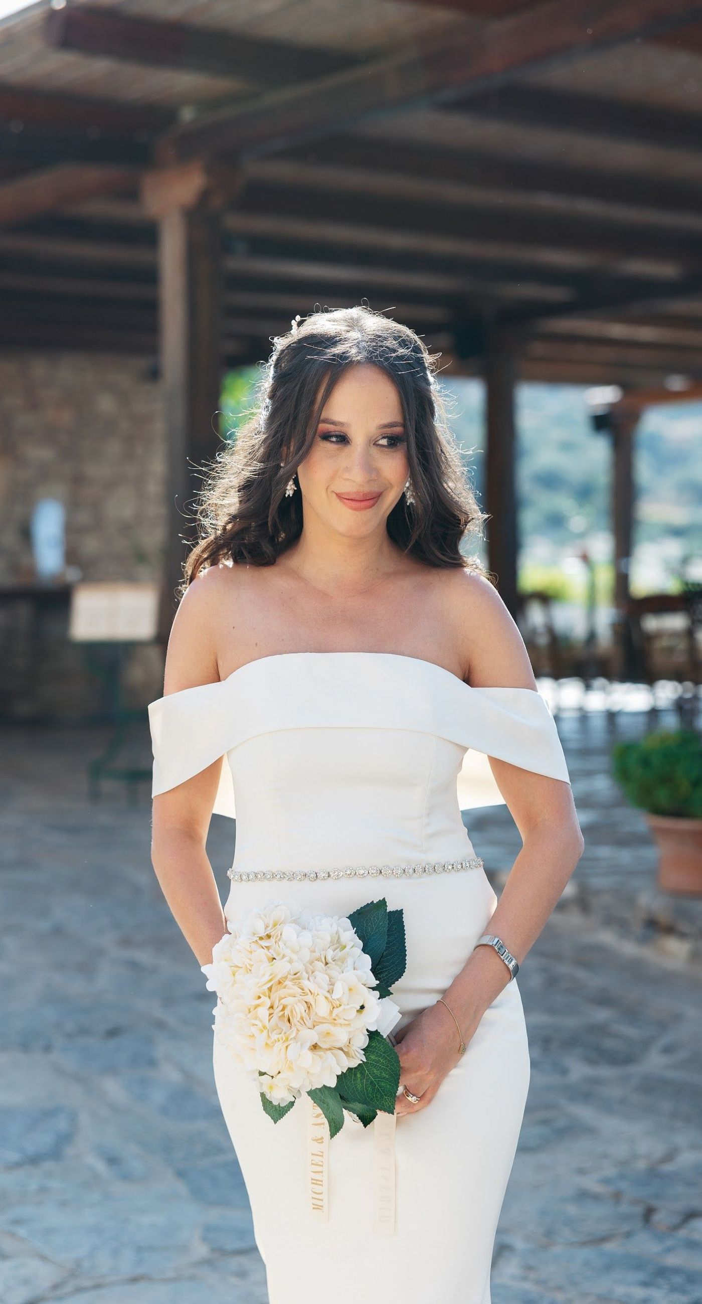 Andria & Alan - Bathed in the golden glow of a setting sun, this moment exudes an elegant blend of warmth and romance. The gentle hues of greenery and the soft embrace of light create a serene ambiance, perfectly framing the delicate embroidery of a bridal gown. The subtle interplay of shadow and light, with touches of white and green flowers, enhances the luxurious simplicity of the scene. This exquisite piece captures the essence of an enchanting outdoor celebration, where nature and elegance harmoniously unite, offering a timeless backdrop for cherished memories. - Photo 7