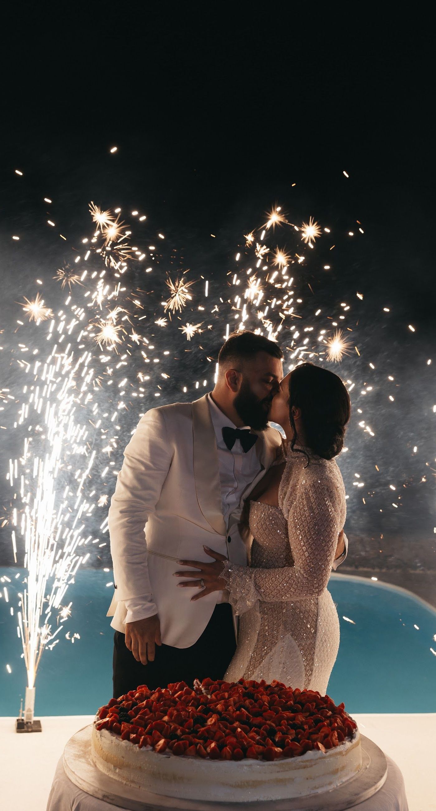 Armita & Azad - A vision of elegance unfolds under a canopy of ethereal blue foliage, accented with white blooms, creating a stunning backdrop for a couple standing in harmonious contrast. Their attire, a dance of monochrome elegance, complements the serene ambiance, while the azure sky and distant cliffs whisper of a hidden paradise. The floor is adorned with cascading white roses, framing the scene with pure grace. The location, with its tranquil vibes and breathtaking views, enhances the overall aesthetic, showcasing a perfect blend of nature and sophistication. This breathtaking display captures the essence of a dreamlike celebration, elevating the floral artistry to new heights. - Photo 10