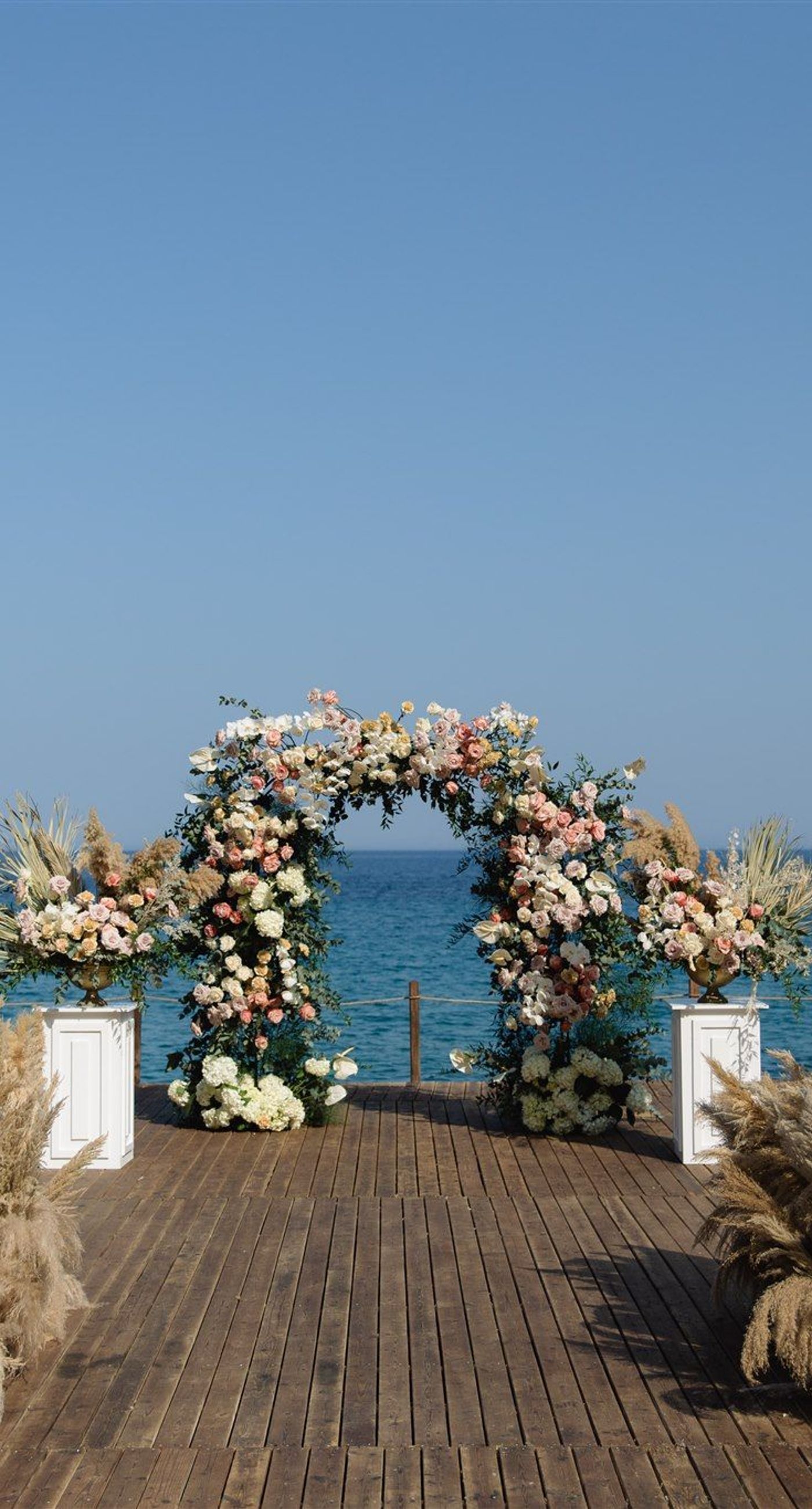 Brittany&James - In a breathtaking dance of romance and nature, the floral masterpiece unfolds with a palette of soft pastels—a delicate harmony of blush pinks, gentle creams, and lush greenery. The exquisite arrangement embraces a dreamy outdoor setting, where elegant bouquets frame a moment stolen from time. The seamless blend of natural beauty and graceful elegance creates an enchanting atmosphere, perfectly capturing the essence of love's tender embrace. This floral artistry evokes a feeling of serene sophistication, enhancing the allure of any special occasion with its timeless charm. - Photo 1