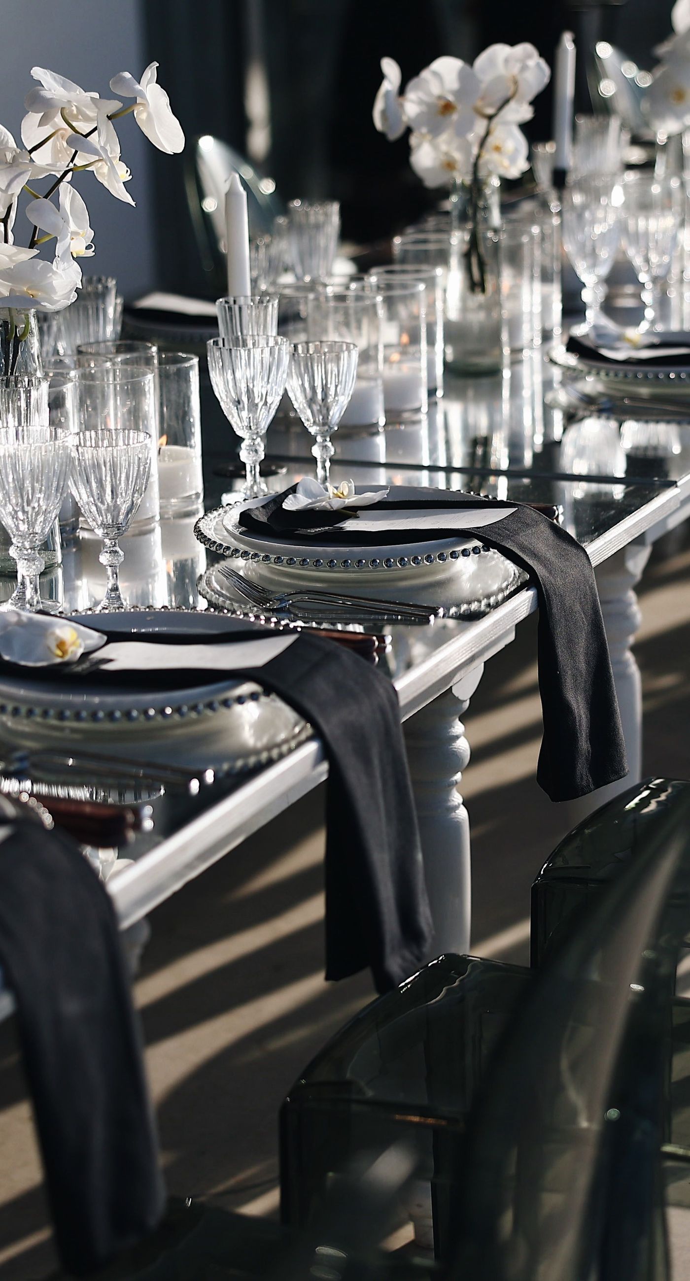 Charlotte & Mateo - In a sunlit scene that marries elegance and joy, a couple strides down an aisle adorned with delicate white petals, while attendees cheerfully shower them with admiration and celebratory petals, embodying a spirit of love and unity. The bride's radiant white gown contrasts beautifully with the subtle greens of the surroundings and the soft blue sky, as the groom's sleek black and white ensemble complements the sophisticated atmosphere. Lush greenery and a graceful arch laced with florals set an enchanting stage, making this moment an exquisite testimony to a florist's craft, capturing both the grandeur and warmth of the occasion. - Photo 5