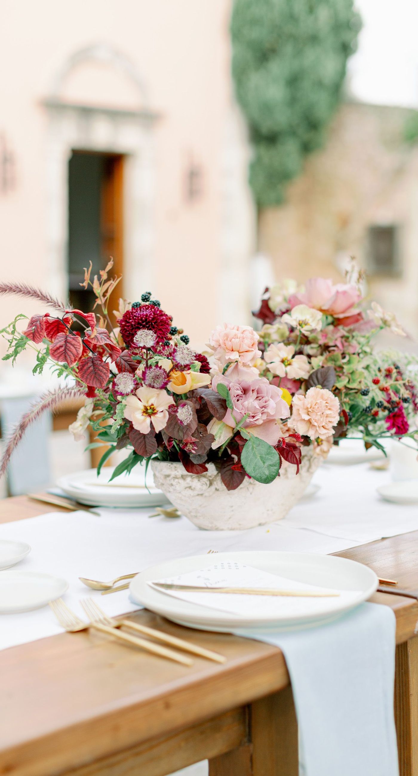 Chiara & Marco - In an elegant dance of romance and subtlety, a couple is enveloped in a moment of intimate anticipation. Their surroundings whisper of nature's abundance, while the soft, muted colors of the bouquet enhance the gentle harmony between the blue suit and white gown. The florist's artistry is evident in the meticulous arrangement of delicate blooms and verdant leaves, highlighting the signature flair for understated sophistication. This serene union of floral grace and human connection brings forth an aesthetic that is both timeless and heartwarming, ideal for a setting that celebrates love and nature in its simplest form. - Photo 8