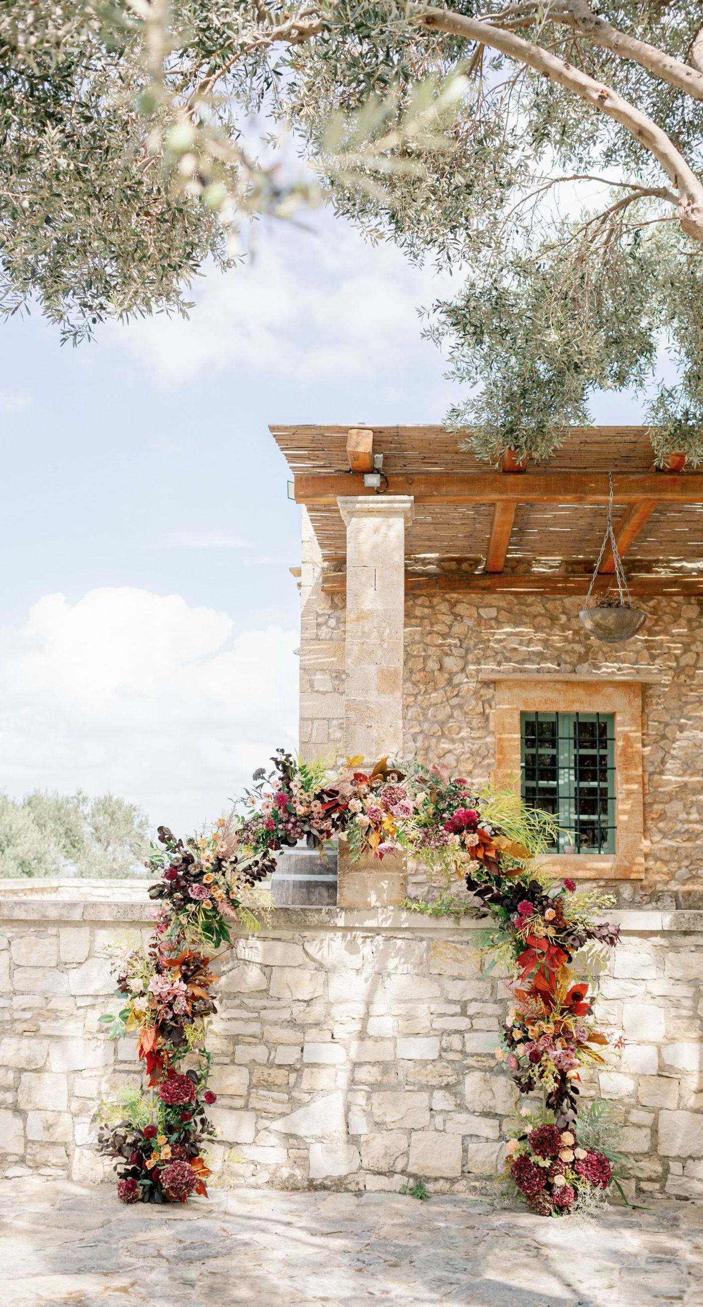 Chiara & Marco - In an elegant dance of romance and subtlety, a couple is enveloped in a moment of intimate anticipation. Their surroundings whisper of nature's abundance, while the soft, muted colors of the bouquet enhance the gentle harmony between the blue suit and white gown. The florist's artistry is evident in the meticulous arrangement of delicate blooms and verdant leaves, highlighting the signature flair for understated sophistication. This serene union of floral grace and human connection brings forth an aesthetic that is both timeless and heartwarming, ideal for a setting that celebrates love and nature in its simplest form. - Photo 2