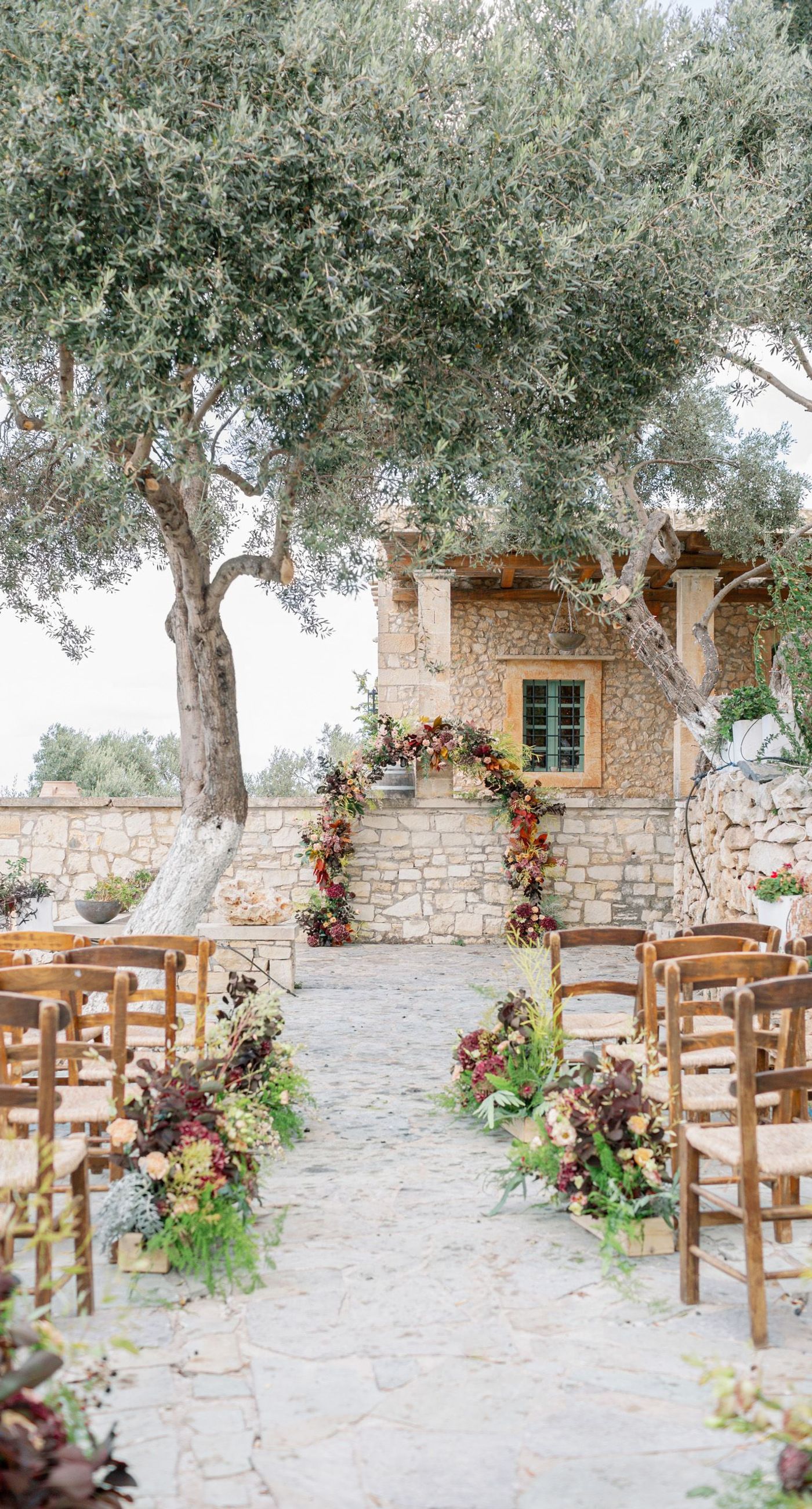 Chiara & Marco - In an elegant dance of romance and subtlety, a couple is enveloped in a moment of intimate anticipation. Their surroundings whisper of nature's abundance, while the soft, muted colors of the bouquet enhance the gentle harmony between the blue suit and white gown. The florist's artistry is evident in the meticulous arrangement of delicate blooms and verdant leaves, highlighting the signature flair for understated sophistication. This serene union of floral grace and human connection brings forth an aesthetic that is both timeless and heartwarming, ideal for a setting that celebrates love and nature in its simplest form. - Photo 1