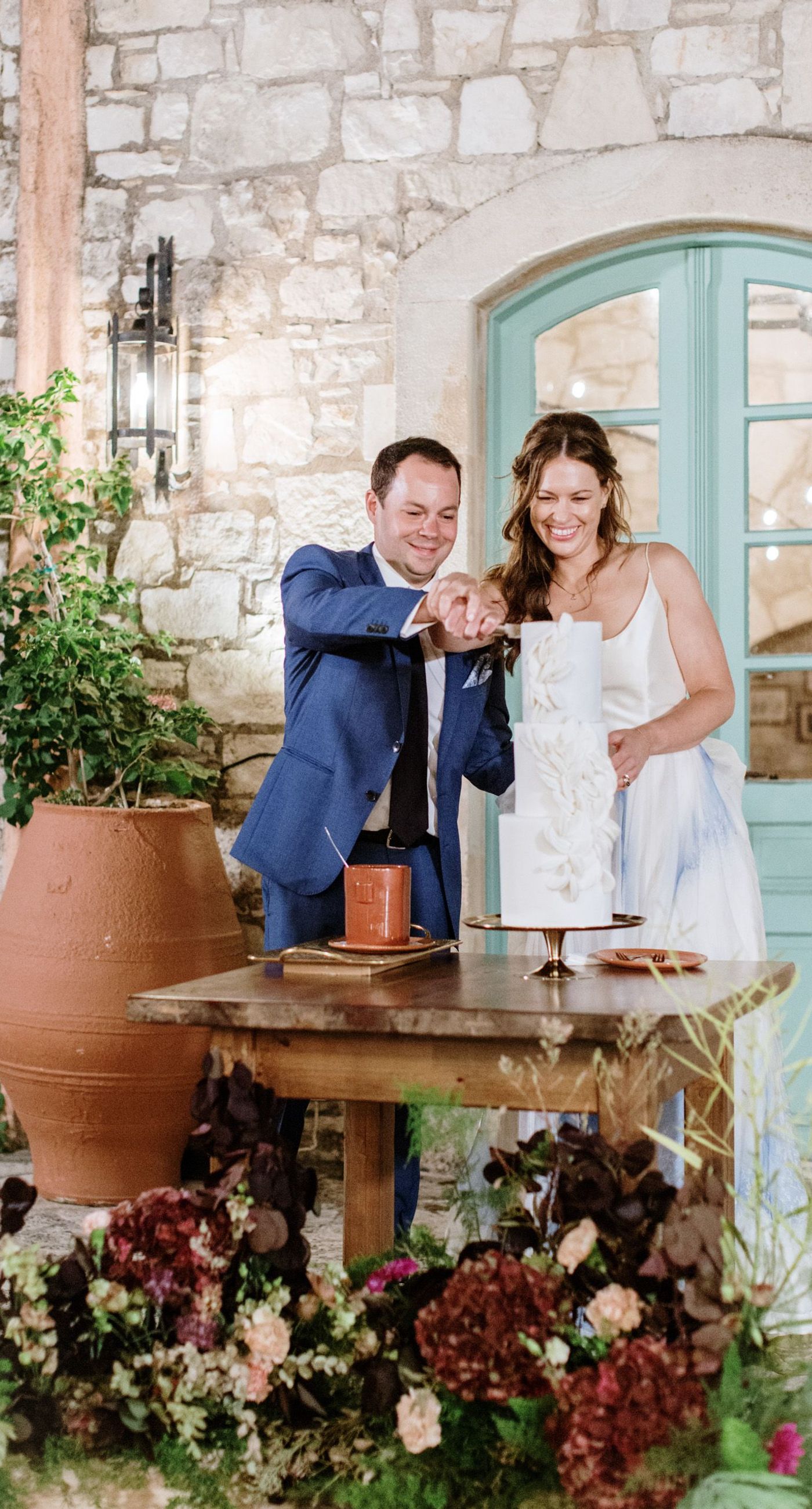 Chiara & Marco - In an elegant dance of romance and subtlety, a couple is enveloped in a moment of intimate anticipation. Their surroundings whisper of nature's abundance, while the soft, muted colors of the bouquet enhance the gentle harmony between the blue suit and white gown. The florist's artistry is evident in the meticulous arrangement of delicate blooms and verdant leaves, highlighting the signature flair for understated sophistication. This serene union of floral grace and human connection brings forth an aesthetic that is both timeless and heartwarming, ideal for a setting that celebrates love and nature in its simplest form. - Photo 13