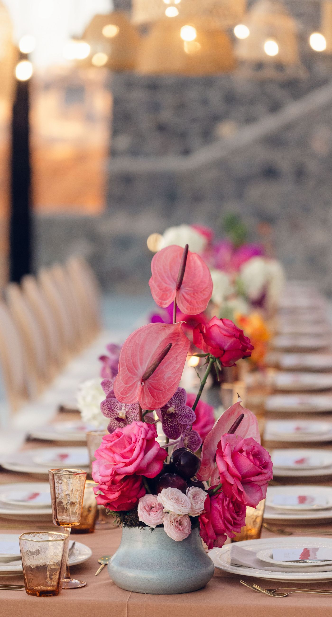 Chris & Jazmin - In a dreamlike setting beneath the soft embrace of the sun, this captivating work embodies a perfect union of elegance and romance. The delicate lace of her gown interlaces with the tender embrace of her partner, creating an ethereal atmosphere amidst the tranquil architecture. A vibrant bouquet bursts with life, featuring an exquisite medley of fuchsia, orange, and deep crimson blooms, each petal whispering tales of timeless love. The muted tones of the setting contrast beautifully with the vivid flowers, offering a glimpse into a serene world where artistry and nature harmonize flawlessly. This presentation speaks to the profound beauty that can blossom in moments of connection. - Photo 9