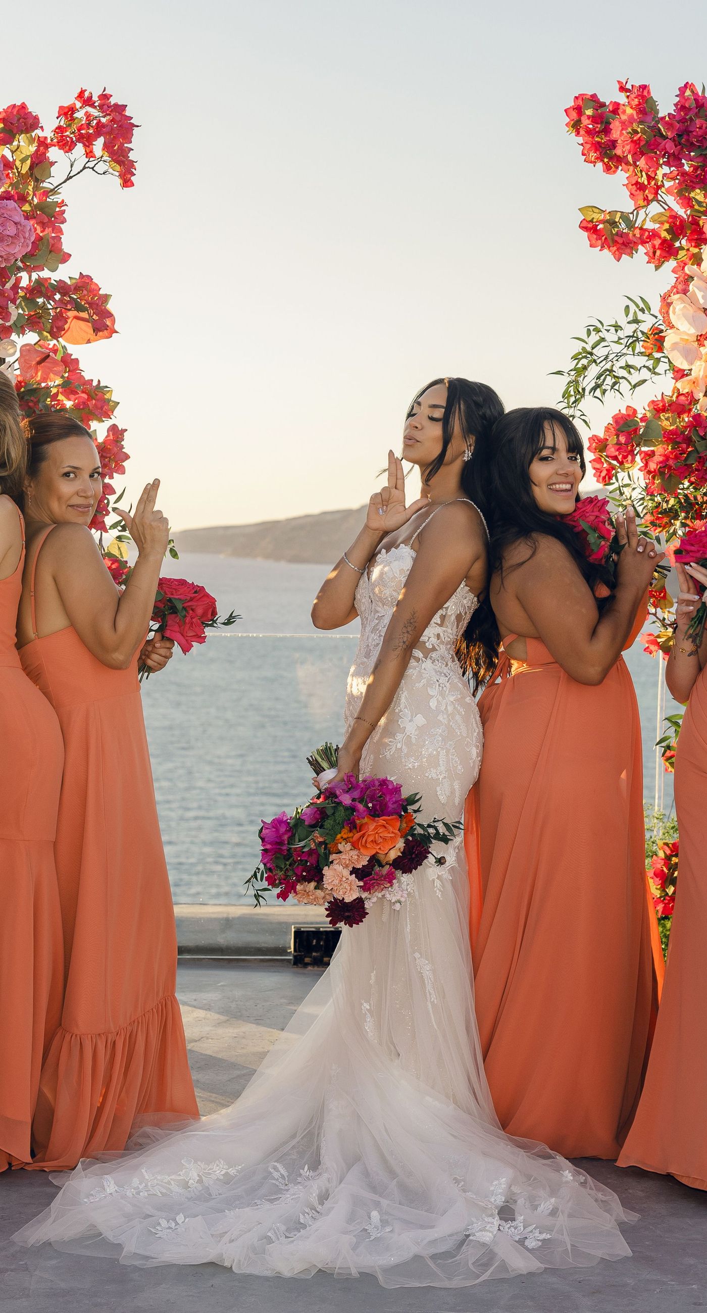 Chris & Jazmin - In a dreamlike setting beneath the soft embrace of the sun, this captivating work embodies a perfect union of elegance and romance. The delicate lace of her gown interlaces with the tender embrace of her partner, creating an ethereal atmosphere amidst the tranquil architecture. A vibrant bouquet bursts with life, featuring an exquisite medley of fuchsia, orange, and deep crimson blooms, each petal whispering tales of timeless love. The muted tones of the setting contrast beautifully with the vivid flowers, offering a glimpse into a serene world where artistry and nature harmonize flawlessly. This presentation speaks to the profound beauty that can blossom in moments of connection. - Photo 4