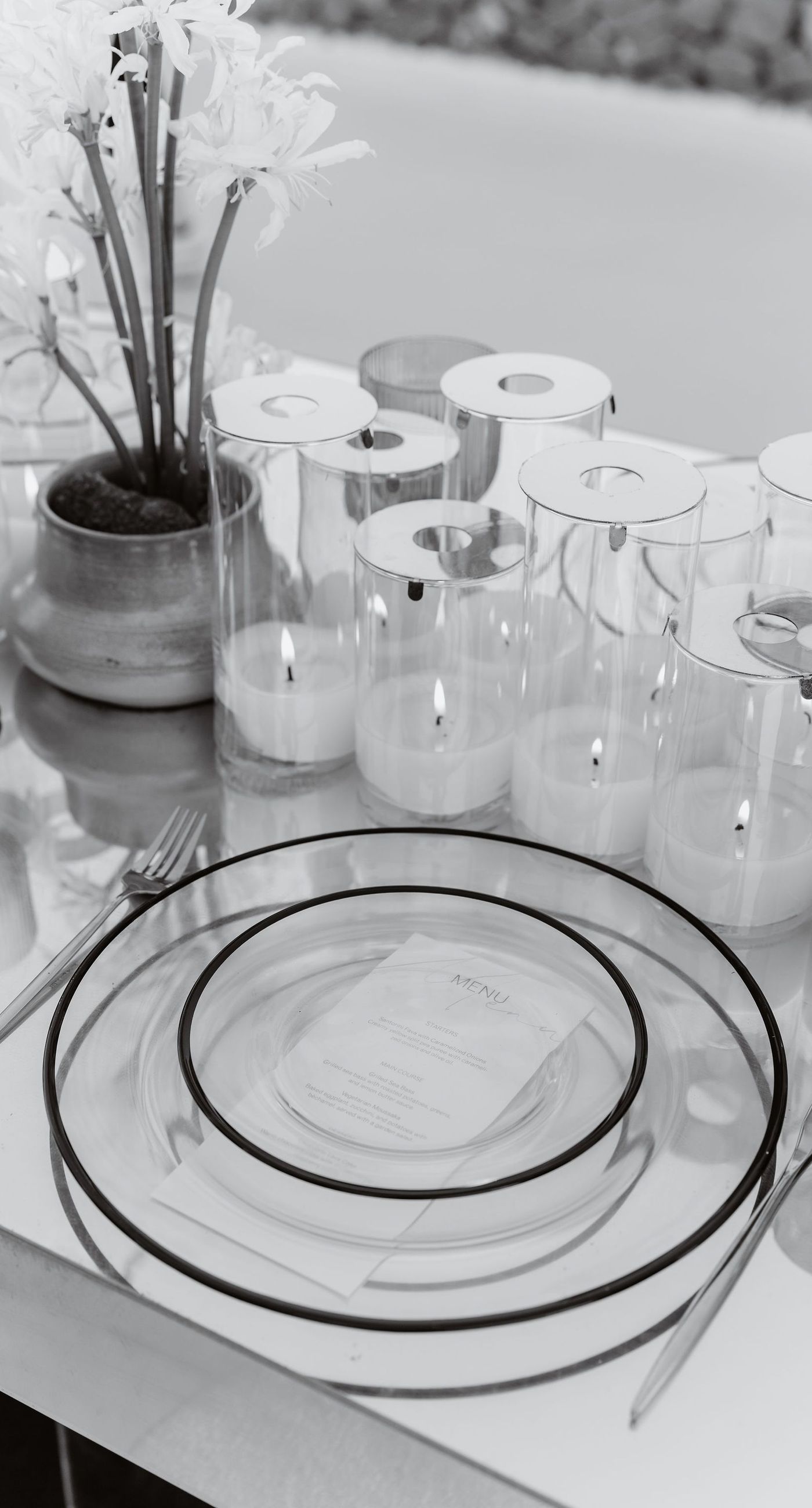 Emily & liam - In this exquisite scene, a couple stands in an ethereal embrace on a glass platform, surrounded by delicate blossoms that mirror the elegance of a sunlit seascape. The subdued pastels of the sunset wash gently over the horizon, casting a serene glow upon the couple and the blooms, creating a harmonious symphony of colors and emotions. The gracefully arranged white flowers echo timeless beauty and sophistication, set against the tranquil backdrop of a distant island. This stunning tableau invites you into a world where nature and romance converge seamlessly, an ideal representation for any florist's portfolio that values artistry and grace. - Photo 7