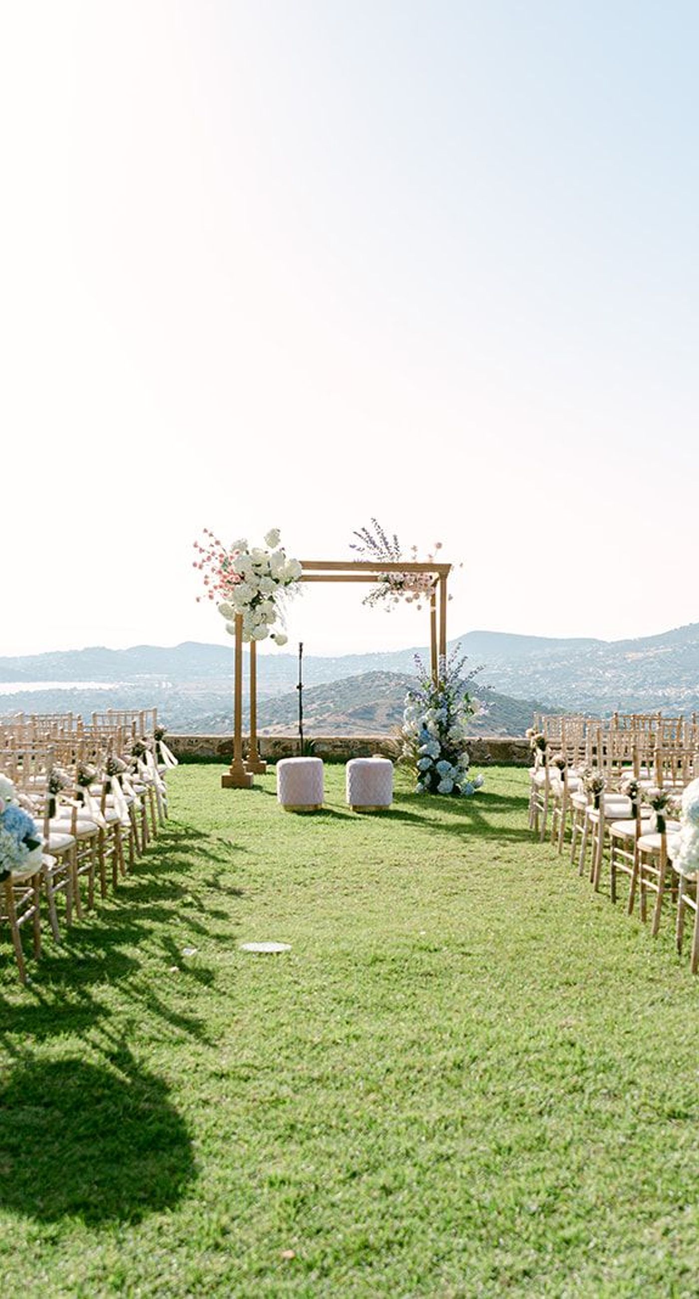 Georges&Marianna - In this exquisite composition, the scene is set with a timeless elegance, captured in a moment of pure joy and connection. The bride's sumptuous white gown cascades gracefully, its off-shoulder design complementing her delicate headpiece, which glimmers subtly under the soft lighting. She is juxtaposed beautifully against the groom's classic black tuxedo, a marriage of sophistication and contemporary flair. The grand marble staircase in the background adds an air of opulence, harmonizing with the earth tones of the venue's refined architecture. Their expressions of happiness, framed by muted hues and elegant lines, evoke an atmosphere of romance and understated luxury, perfect for a portfolio that celebrates life's most beautiful occasions. - Photo 4