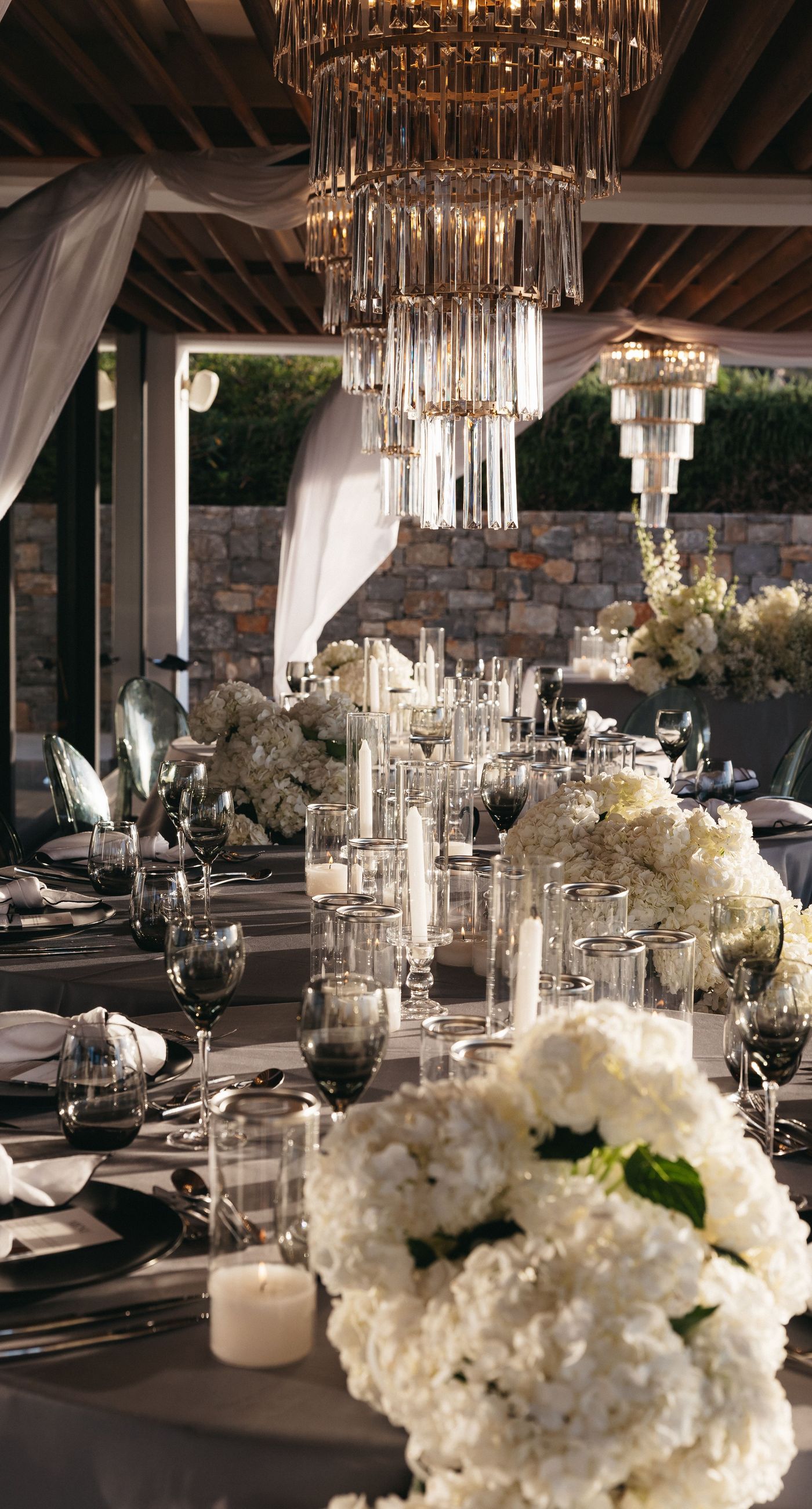 Holly & Mark - In a symphony of elegance and romance, this floral masterpiece frames an intimate moment beneath a brilliant blue sky. The archway, adorned with lush clusters of pristine white blooms and delicate baby's breath, creates a dreamy, ethereal backdrop that captures the essence of sophistication and serenity. The reflective surface beneath adds a touch of modernity, while the gentle ocean breeze seems to whisper promises of a new beginning. This harmonious blend of nature’s finest elements crafts a breathtaking scene, perfect for any discerning couple seeking a timeless and enchanting setting for their special day. - Photo 7