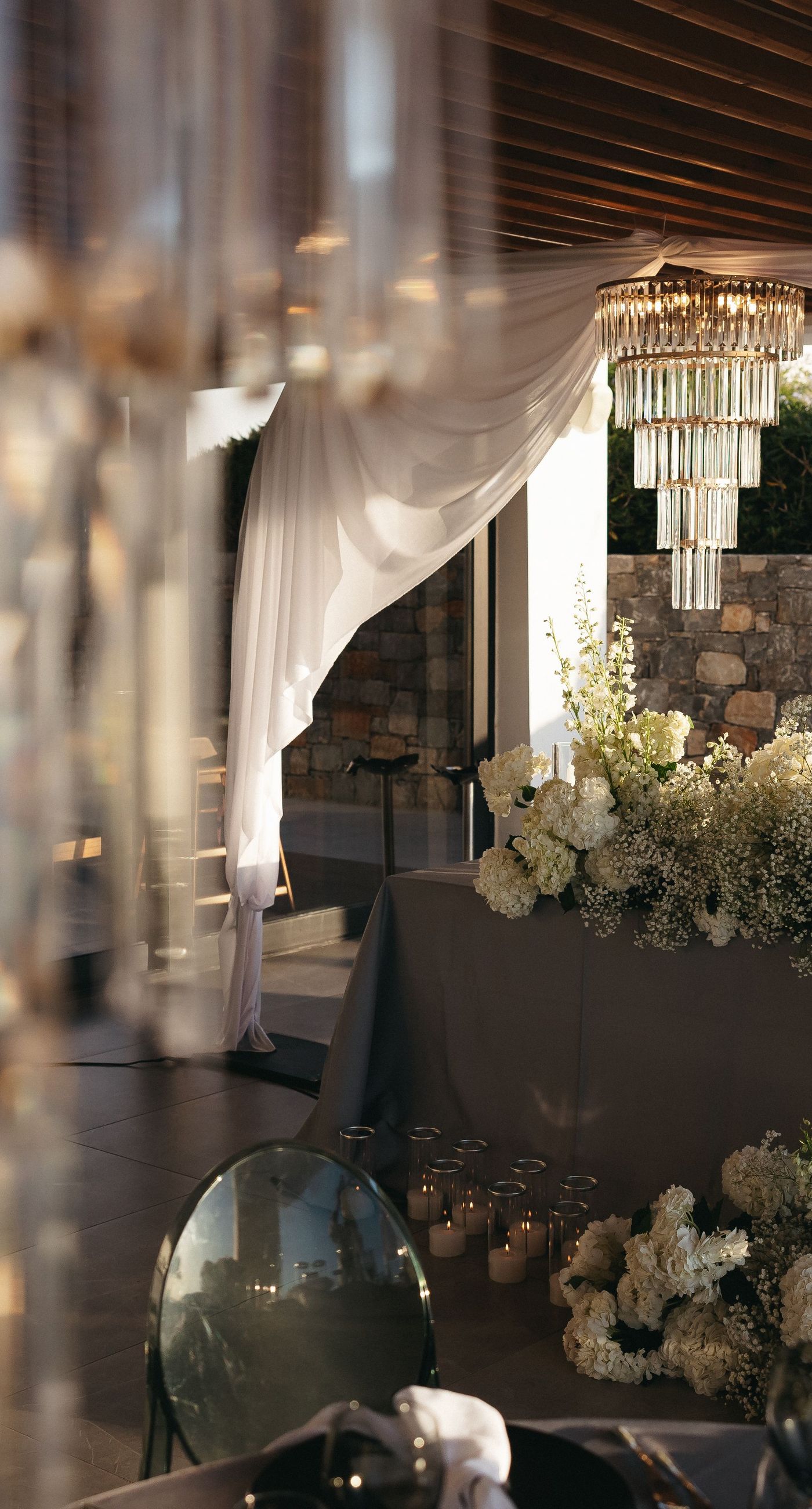 Holly & Mark - In a symphony of elegance and romance, this floral masterpiece frames an intimate moment beneath a brilliant blue sky. The archway, adorned with lush clusters of pristine white blooms and delicate baby's breath, creates a dreamy, ethereal backdrop that captures the essence of sophistication and serenity. The reflective surface beneath adds a touch of modernity, while the gentle ocean breeze seems to whisper promises of a new beginning. This harmonious blend of nature’s finest elements crafts a breathtaking scene, perfect for any discerning couple seeking a timeless and enchanting setting for their special day. - Photo 9