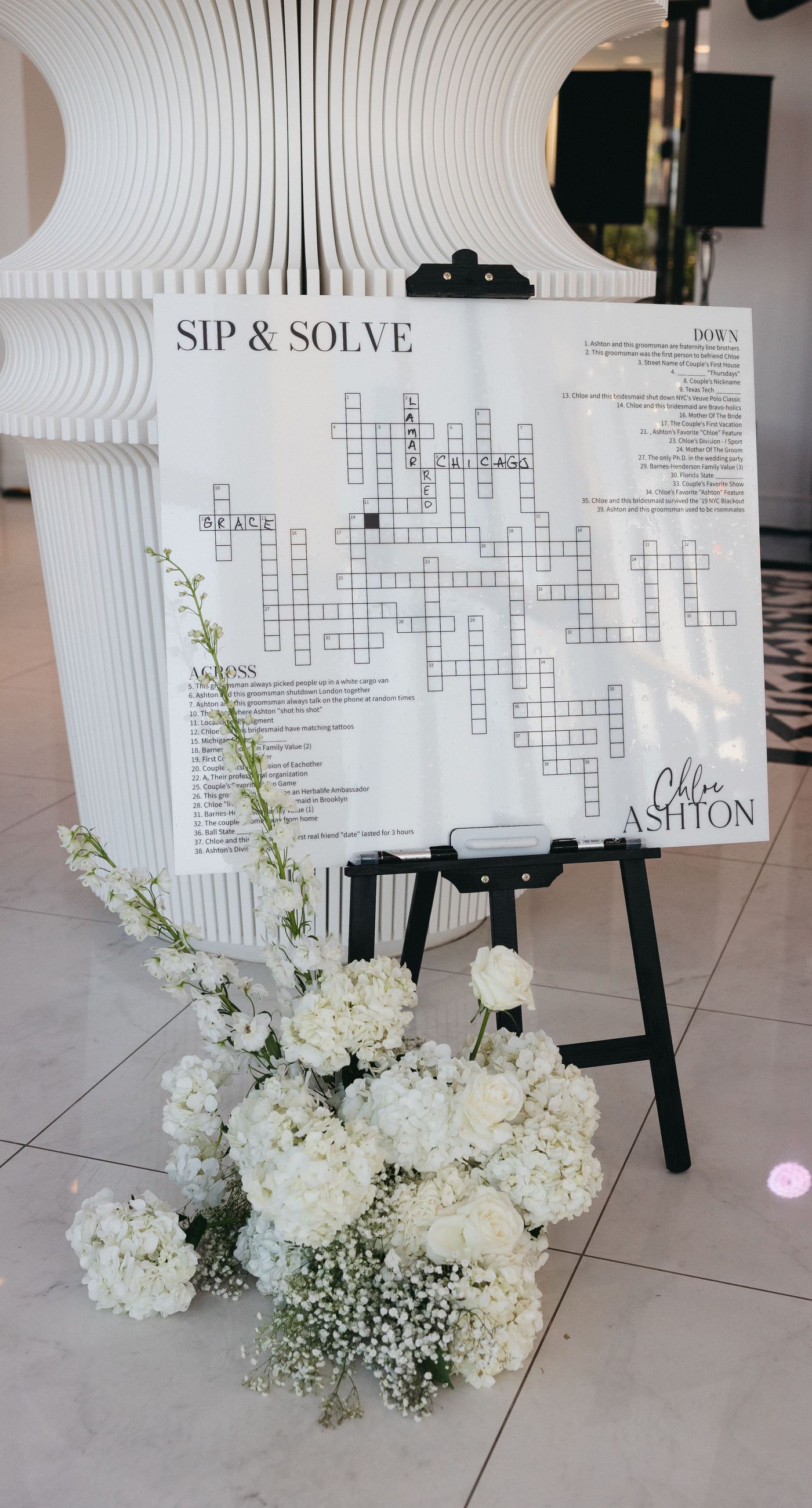 Holly & Mark - In a symphony of elegance and romance, this floral masterpiece frames an intimate moment beneath a brilliant blue sky. The archway, adorned with lush clusters of pristine white blooms and delicate baby's breath, creates a dreamy, ethereal backdrop that captures the essence of sophistication and serenity. The reflective surface beneath adds a touch of modernity, while the gentle ocean breeze seems to whisper promises of a new beginning. This harmonious blend of nature’s finest elements crafts a breathtaking scene, perfect for any discerning couple seeking a timeless and enchanting setting for their special day. - Photo 13