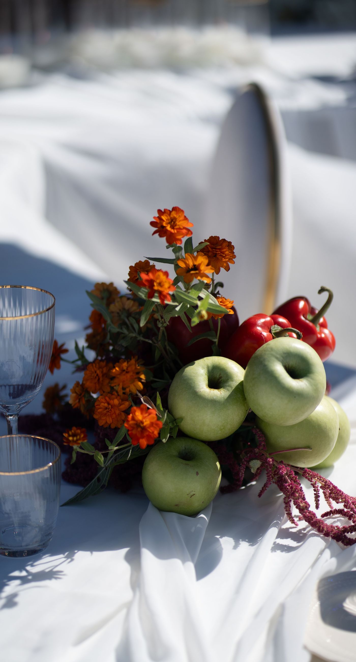 Isabella & Oliver - Under a clear blue sky, what unfolds is an ethereal expression of elegance and romance. The serene backdrop of vast, azure waters beautifully contrasts with the soft, delicate whites of the cascading petals, creating a scene both harmonious and enchanting. Meticulously arranged roses in gentle pinks and creams line the path, complementing the timeless lace and flowing structure of the bride's gown, while the groom's classic black suit adds a touch of refined sophistication. The graceful drapery, kissed by the gentle breeze, frames this moment of joy and forms a masterpiece of floral artistry, balancing nature's serenity with bridal grandeur. - Photo 9