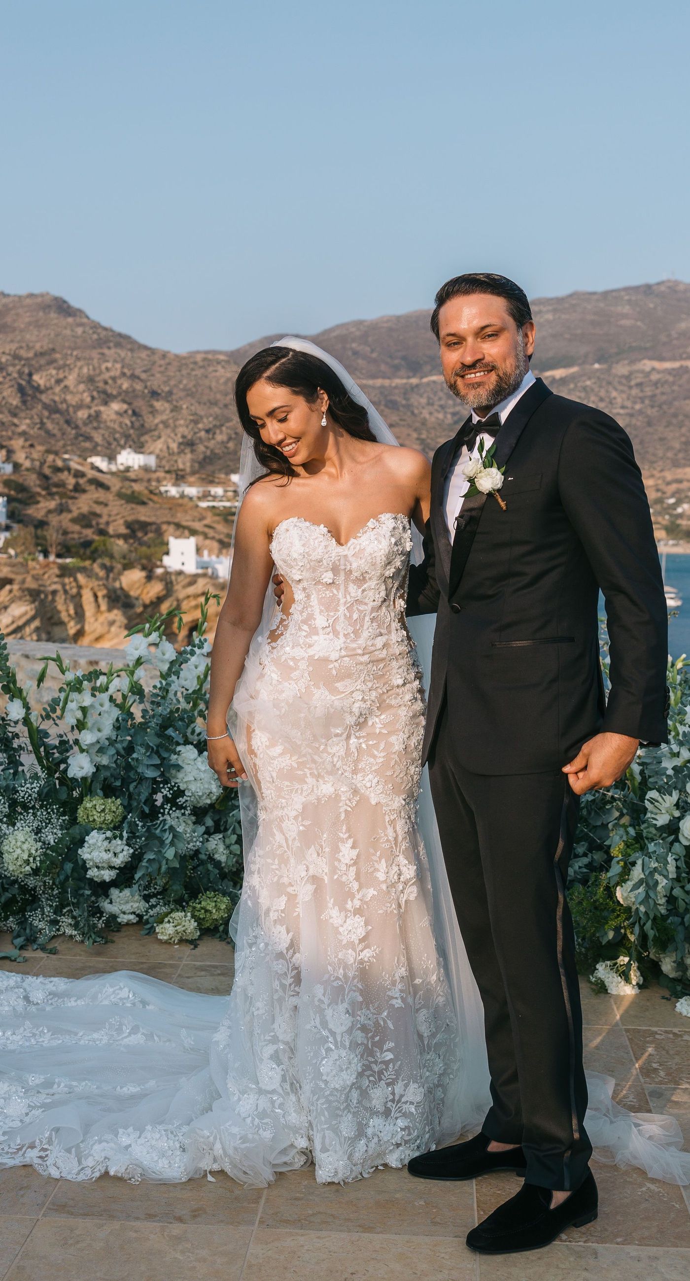 Kala & Kerwin - Bathed in the warm glow of a setting sun, the bouquet of creamy white blooms and eucalyptus whispers elegance and romance. It complements the ethereal lace details of the attire, creating a harmonious blend of textures and colors. The backdrop of rustic stone steps hints at a location where nature and romance intertwine seamlessly, offering a timeless, serene beauty. This work encapsulates a moment of profound connection and grace, emphasizing the pure emotional essence captured on a special day. - Photo 2