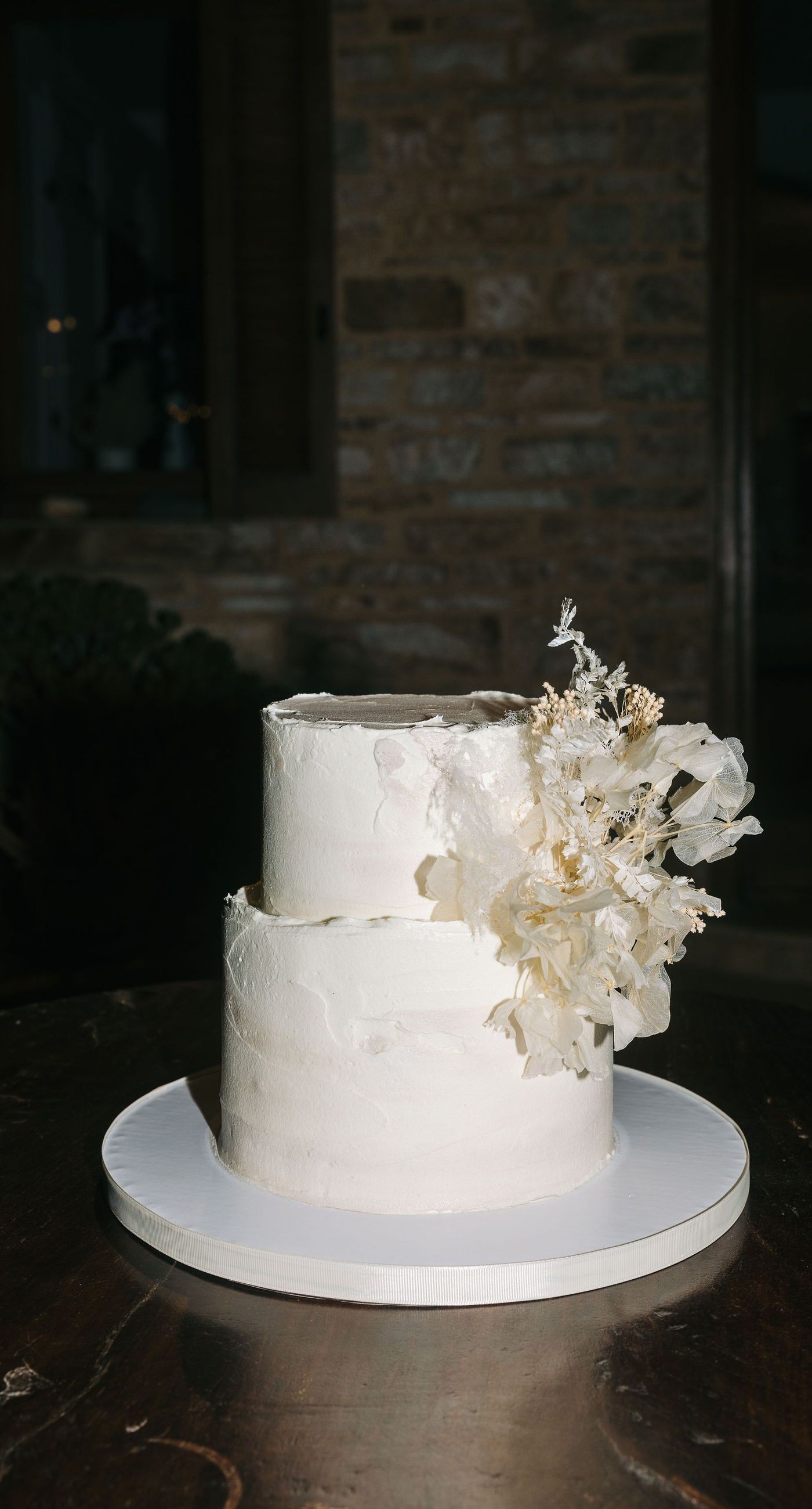 Kala & Kerwin - Bathed in the warm glow of a setting sun, the bouquet of creamy white blooms and eucalyptus whispers elegance and romance. It complements the ethereal lace details of the attire, creating a harmonious blend of textures and colors. The backdrop of rustic stone steps hints at a location where nature and romance intertwine seamlessly, offering a timeless, serene beauty. This work encapsulates a moment of profound connection and grace, emphasizing the pure emotional essence captured on a special day. - Photo 16