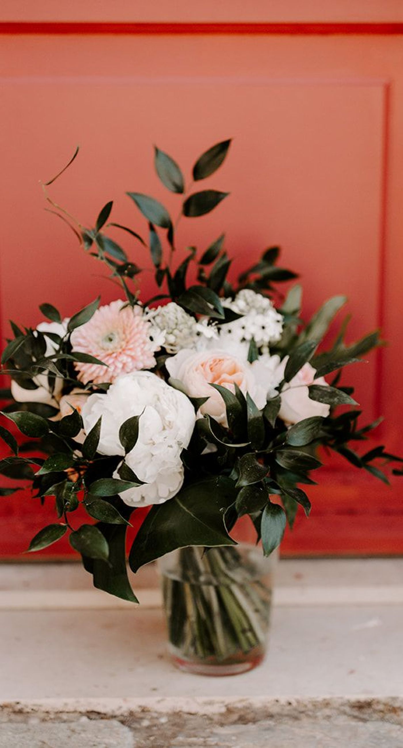 Ketty & Smith - In a symphony of soft pink hues and delicate floral arrangements, the romance of this work unfolds against a backdrop of timeless charm. The couple stands enveloped in a misty blush, their intimate embrace framed by an elegant stone archway, exuding elegance and warmth. The bride's bouquet, a harmonious blend of greenery and pastel blossoms, complements the sophisticated navy of the groom's suit, while the gentle palette of the setting evokes an ethereal, dreamlike quality. Every element is curated with graceful precision, creating a tapestry of love and beauty that is both refined and captivating. - Photo 3