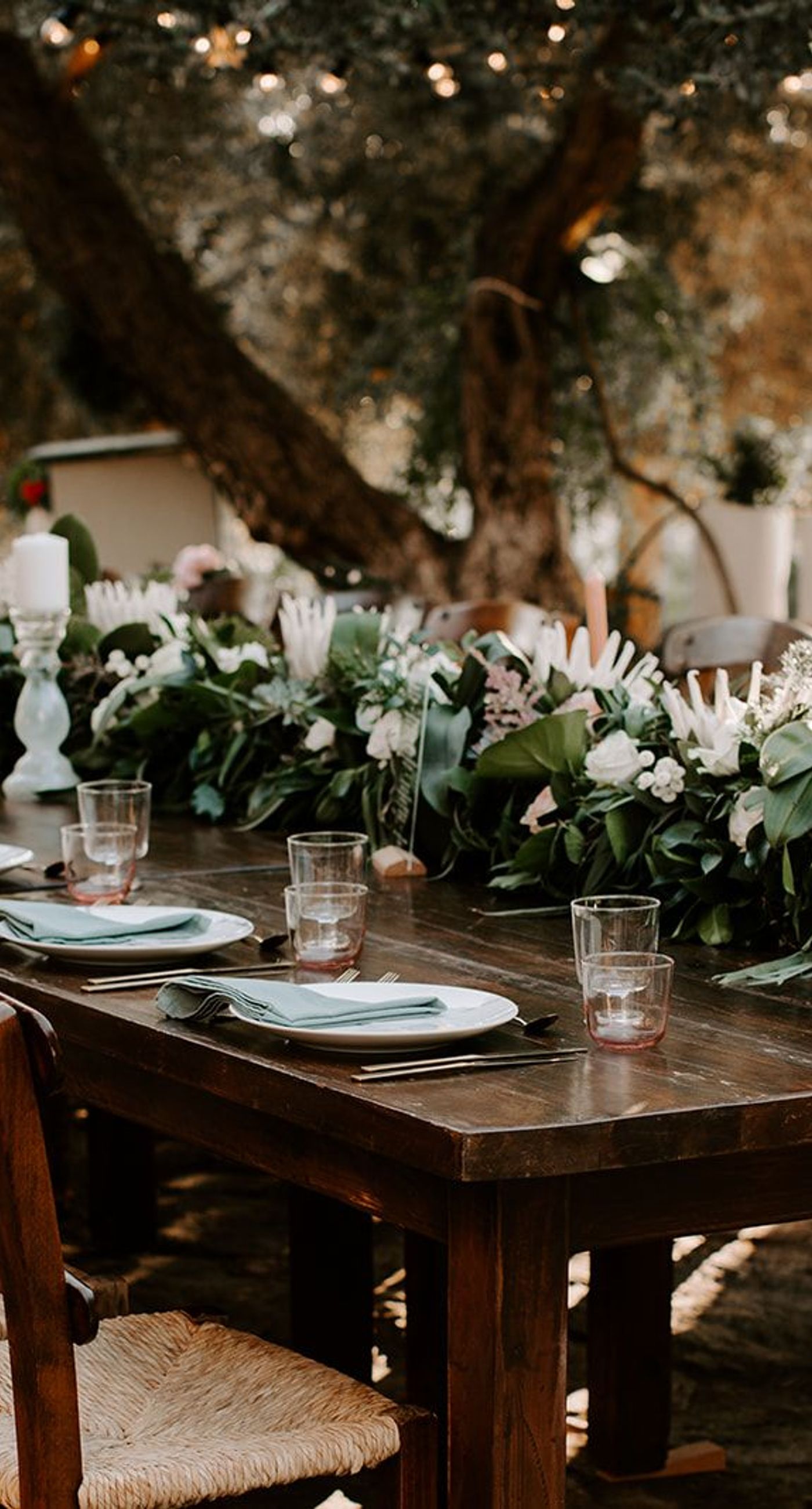 Ketty & Smith - In a symphony of soft pink hues and delicate floral arrangements, the romance of this work unfolds against a backdrop of timeless charm. The couple stands enveloped in a misty blush, their intimate embrace framed by an elegant stone archway, exuding elegance and warmth. The bride's bouquet, a harmonious blend of greenery and pastel blossoms, complements the sophisticated navy of the groom's suit, while the gentle palette of the setting evokes an ethereal, dreamlike quality. Every element is curated with graceful precision, creating a tapestry of love and beauty that is both refined and captivating. - Photo 1