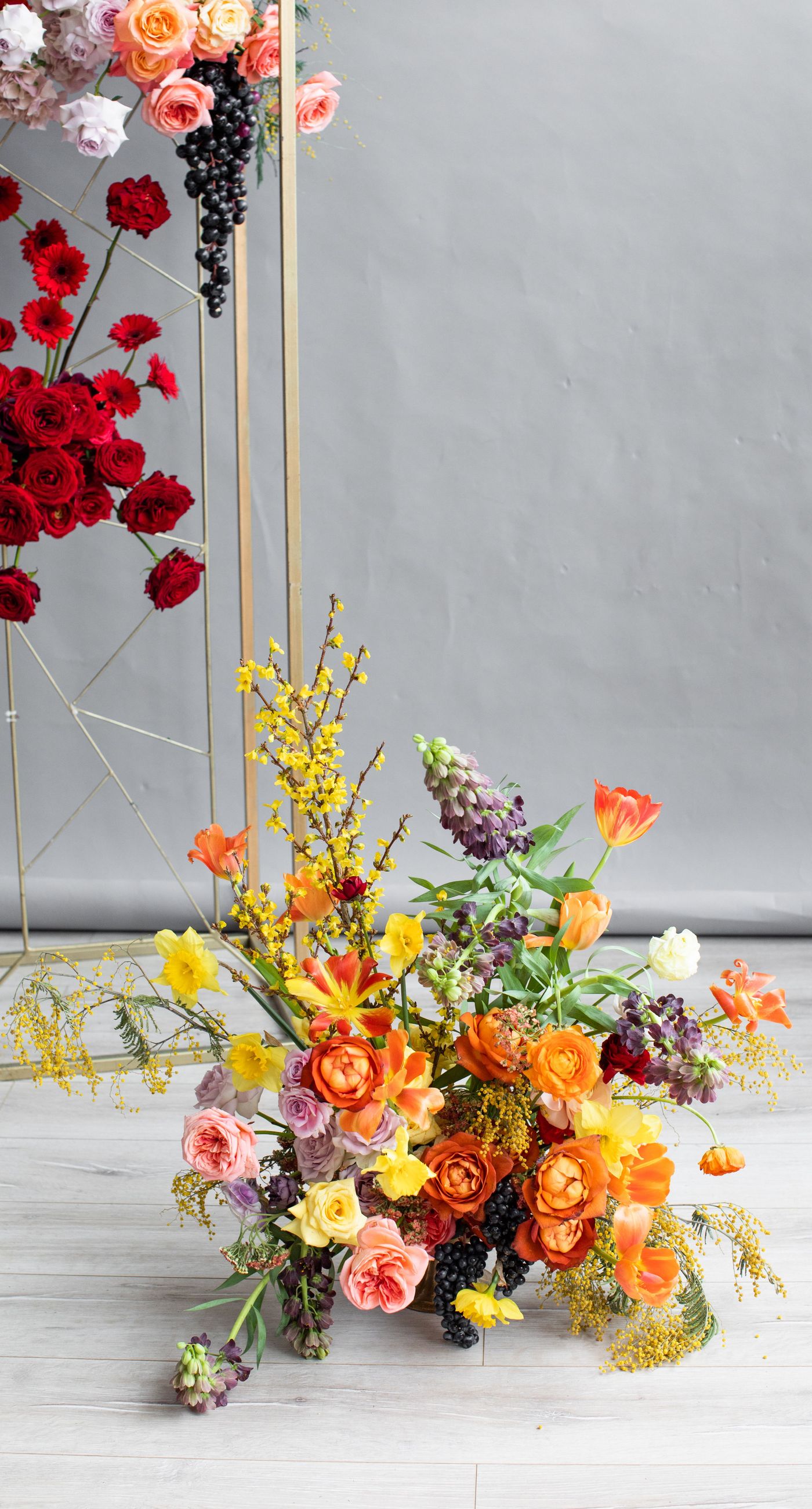 Medieval Dinner - In a symphony of colors, this floral arrangement weaves together vibrancy and elegance, creating an aesthetic that feels both timeless and contemporary. The vivid reds, yellows, and oranges of the blooms contrast strikingly against a soft, neutral backdrop, while a rich, wine-colored robe adds a touch of opulence. Surrounded by a lush abundance of fruits and elegant tableware, the setting evokes a sense of refined abundance, as if captured in a modern-day still life. The arrangement harmoniously balances the natural and the curated, transforming the space into a living work of art, and serving as a striking centerpiece for a florist's creative portfolio.
 - Photo 4