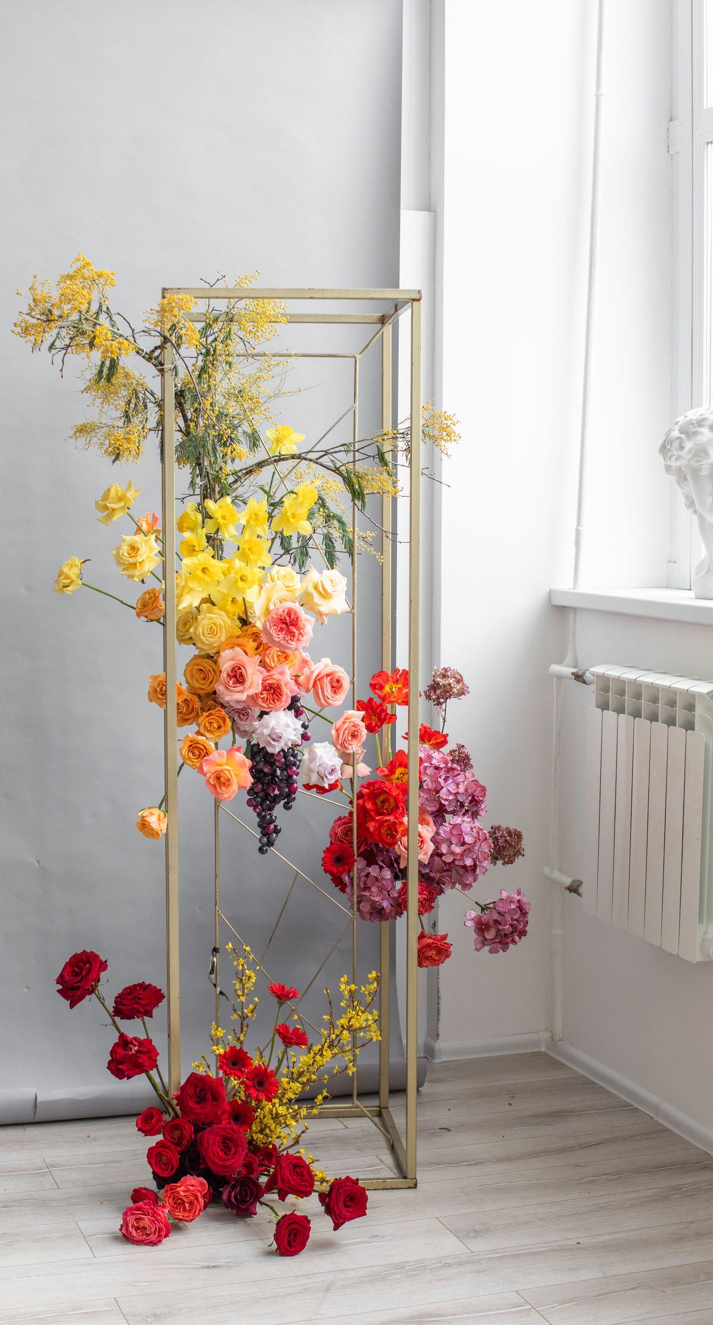 Medieval Dinner - In a symphony of colors, this floral arrangement weaves together vibrancy and elegance, creating an aesthetic that feels both timeless and contemporary. The vivid reds, yellows, and oranges of the blooms contrast strikingly against a soft, neutral backdrop, while a rich, wine-colored robe adds a touch of opulence. Surrounded by a lush abundance of fruits and elegant tableware, the setting evokes a sense of refined abundance, as if captured in a modern-day still life. The arrangement harmoniously balances the natural and the curated, transforming the space into a living work of art, and serving as a striking centerpiece for a florist's creative portfolio.
 - Photo 7