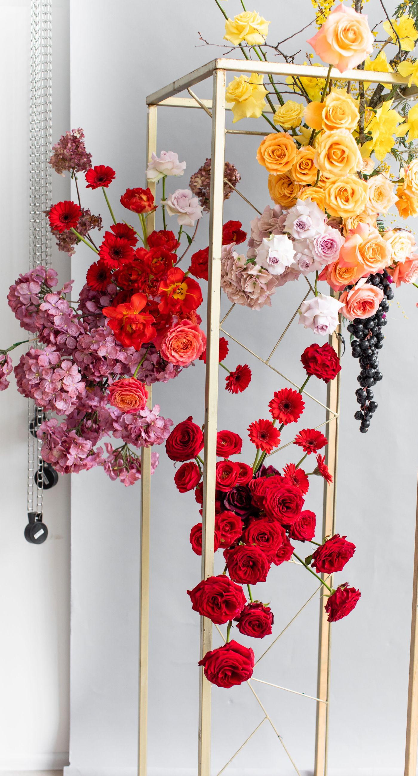 Medieval Dinner - In a symphony of colors, this floral arrangement weaves together vibrancy and elegance, creating an aesthetic that feels both timeless and contemporary. The vivid reds, yellows, and oranges of the blooms contrast strikingly against a soft, neutral backdrop, while a rich, wine-colored robe adds a touch of opulence. Surrounded by a lush abundance of fruits and elegant tableware, the setting evokes a sense of refined abundance, as if captured in a modern-day still life. The arrangement harmoniously balances the natural and the curated, transforming the space into a living work of art, and serving as a striking centerpiece for a florist's creative portfolio.
 - Photo 6