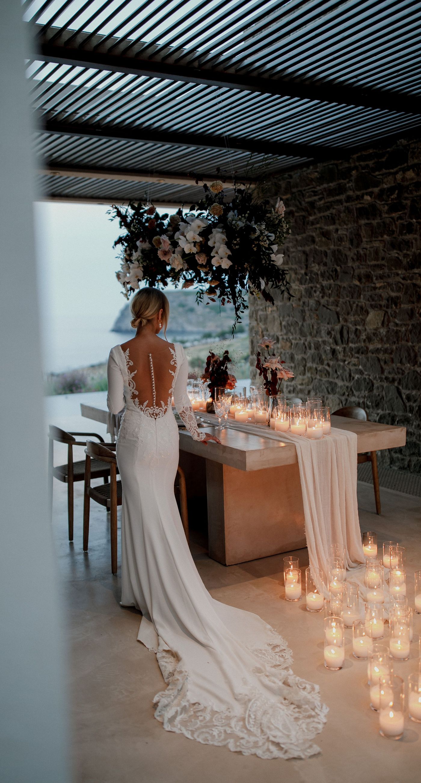 Monika & Ryan - Under a gentle sky that meets a serene coastline, a beautifully crafted floral arch frames an intimate moment of joy and elegance. Soft blush roses and pristine white orchids cascade amid deep burgundy leaves, creating a lush tapestry that echoes the surrounding natural beauty. The harmonious blend of textures and muted colors evokes a sense of timeless romance, making each element of the design feel both organic and artful. The scene captures the essence of a tranquil seaside celebration, where nature's breathtaking backdrop complements the exquisite floral artistry. - Photo 4