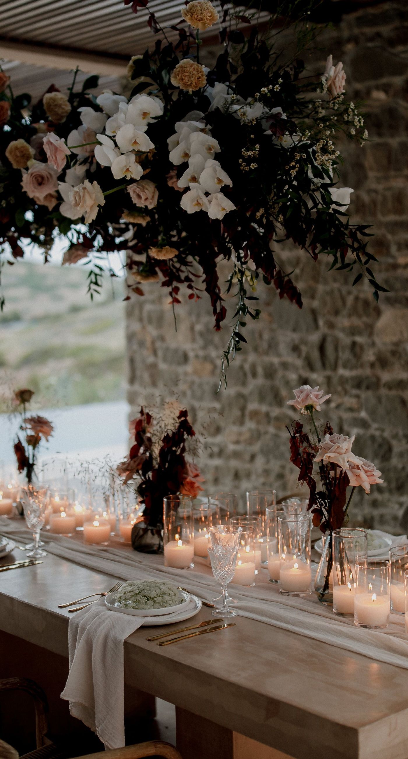 Monika & Ryan - Under a gentle sky that meets a serene coastline, a beautifully crafted floral arch frames an intimate moment of joy and elegance. Soft blush roses and pristine white orchids cascade amid deep burgundy leaves, creating a lush tapestry that echoes the surrounding natural beauty. The harmonious blend of textures and muted colors evokes a sense of timeless romance, making each element of the design feel both organic and artful. The scene captures the essence of a tranquil seaside celebration, where nature's breathtaking backdrop complements the exquisite floral artistry. - Photo 7