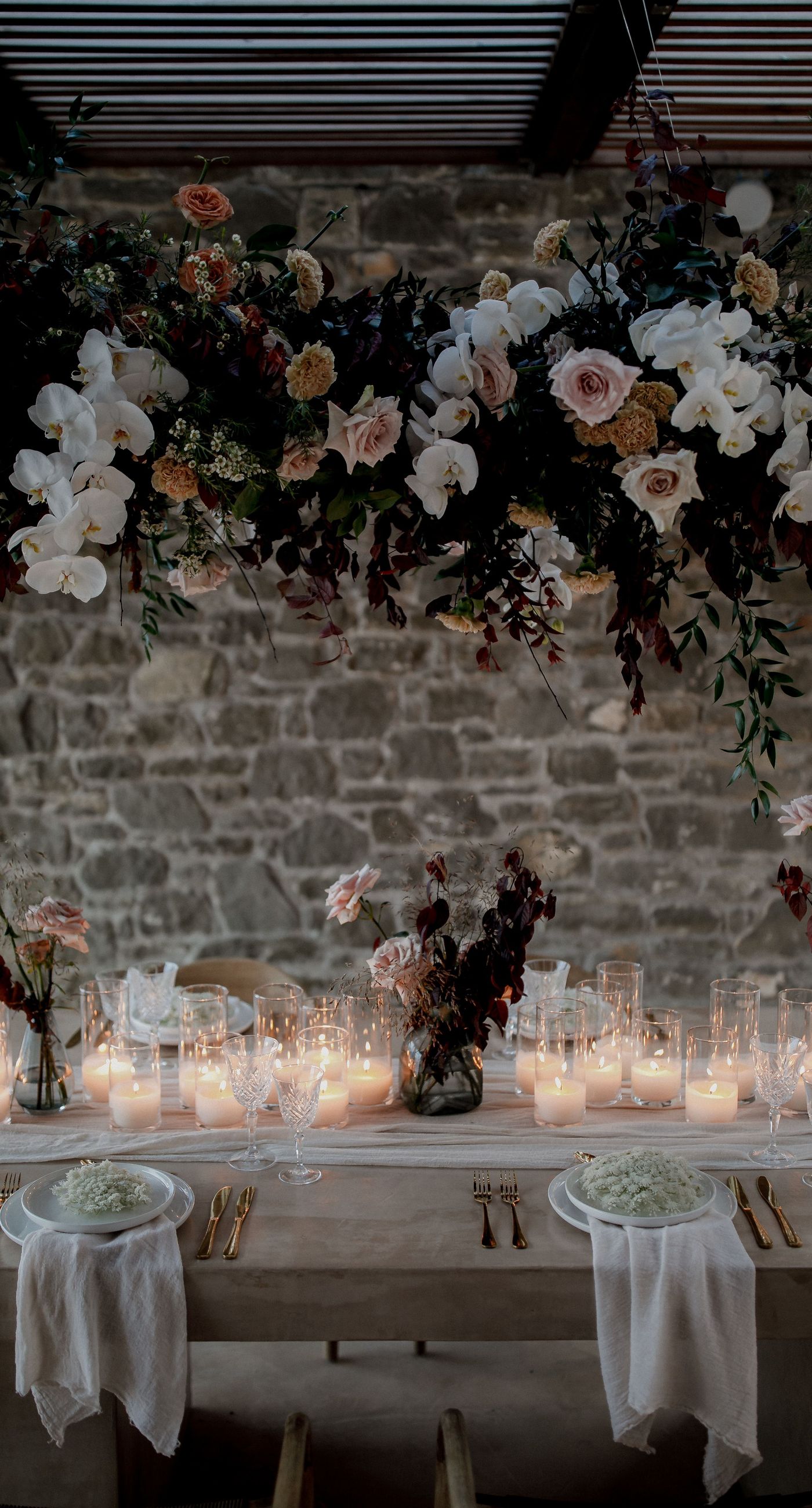 Monika & Ryan - Under a gentle sky that meets a serene coastline, a beautifully crafted floral arch frames an intimate moment of joy and elegance. Soft blush roses and pristine white orchids cascade amid deep burgundy leaves, creating a lush tapestry that echoes the surrounding natural beauty. The harmonious blend of textures and muted colors evokes a sense of timeless romance, making each element of the design feel both organic and artful. The scene captures the essence of a tranquil seaside celebration, where nature's breathtaking backdrop complements the exquisite floral artistry. - Photo 6