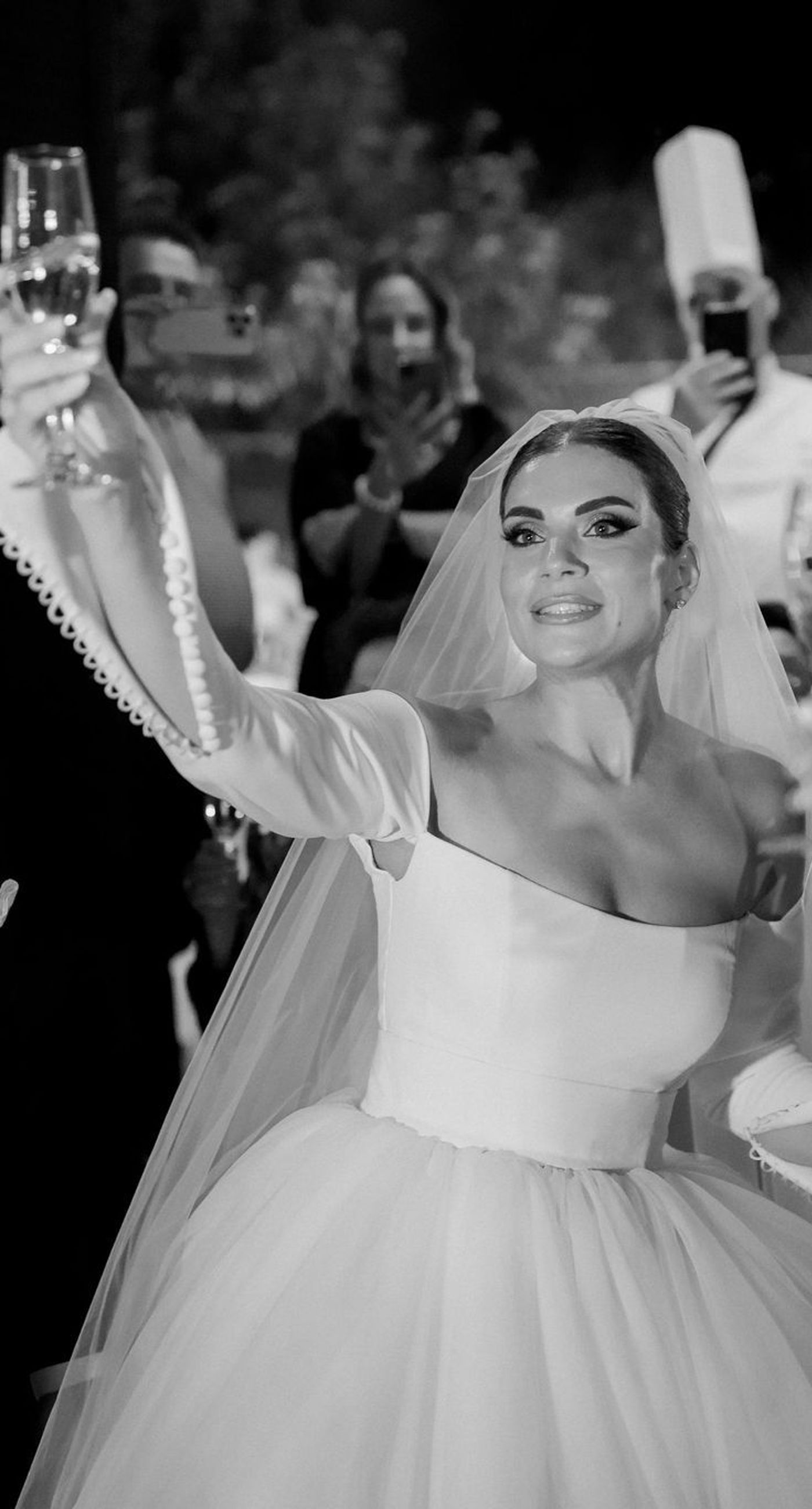 Natalia & John  - Amidst a cascade of ivory roses and lush greenery, an elegantly composed scene unfolds, embodying a timeless romance. The bride, draped in a voluminous white gown, holds a delicate bouquet of blooms that mirrors the floral splendor surrounding her. The groom, in classic black tie, complements the serene palette with a touch of timeless elegance. This artistic composition brings together the soft whispers of petals and the gentle embrace of forgotten days, creating a vibrant harmony between nature's charm and heartfelt human moments. The florals, artfully arranged, create an enchanting backdrop that speaks of new beginnings and enduring beauty. - Photo 14