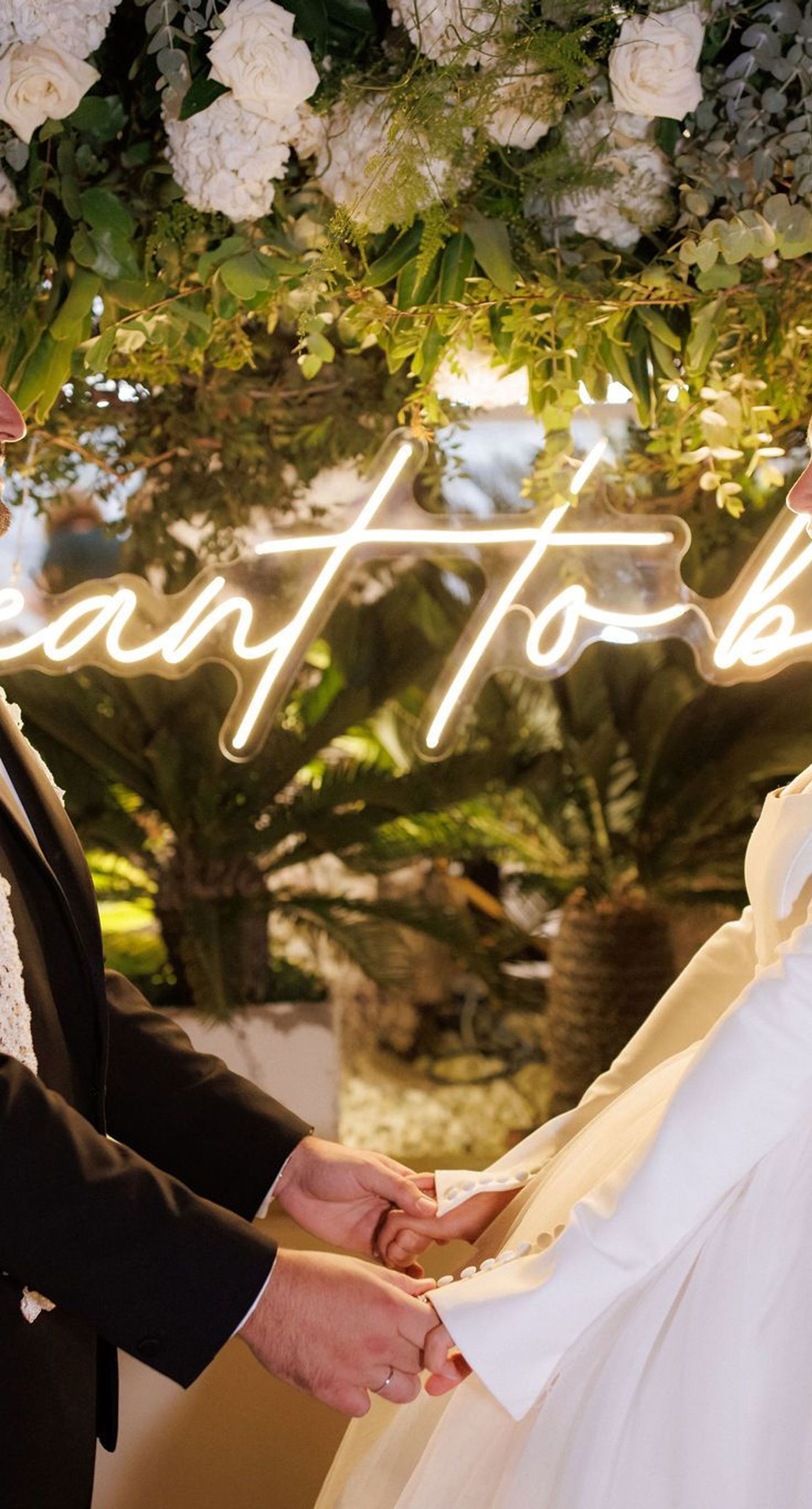 Natalia & John  - Amidst a cascade of ivory roses and lush greenery, an elegantly composed scene unfolds, embodying a timeless romance. The bride, draped in a voluminous white gown, holds a delicate bouquet of blooms that mirrors the floral splendor surrounding her. The groom, in classic black tie, complements the serene palette with a touch of timeless elegance. This artistic composition brings together the soft whispers of petals and the gentle embrace of forgotten days, creating a vibrant harmony between nature's charm and heartfelt human moments. The florals, artfully arranged, create an enchanting backdrop that speaks of new beginnings and enduring beauty. - Photo 13