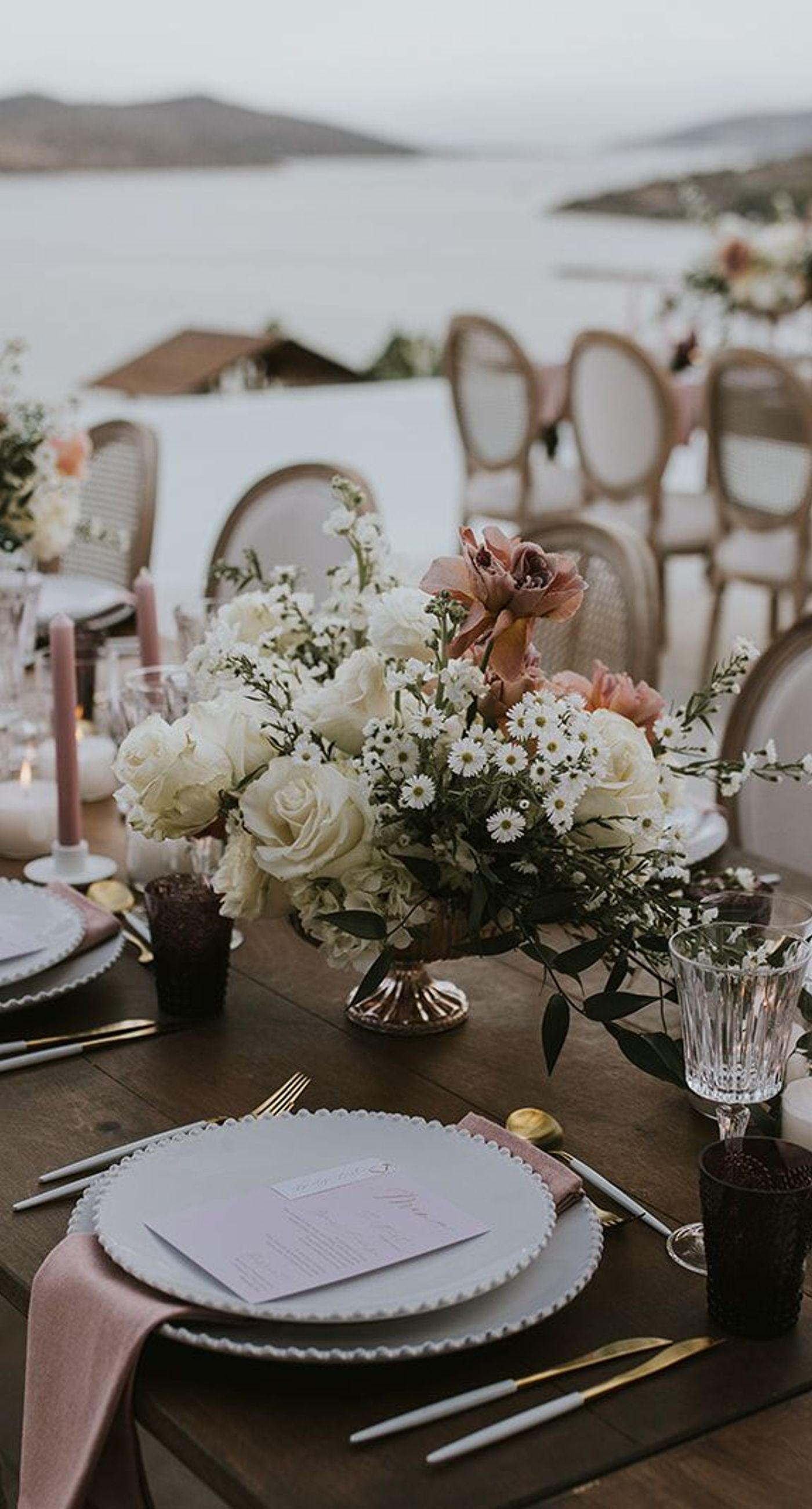 Nina& Samouel - In a beautiful symphony of nature and romance, this scene captures the essence of a perfect coastal celebration. The gentle breeze carries sweet floral whispers as the couple walks amidst a cascade of pastel petals, their smiles reflecting joy and love. The soft blues of the ocean and sky provide a serene backdrop, harmonizing with the lush greenery and delicate whites and pinks of the blooms. This composition encapsulates an idyllic, nature-infused elegance, showcasing the artistry and thoughtful design of the florist's craft. - Photo 6