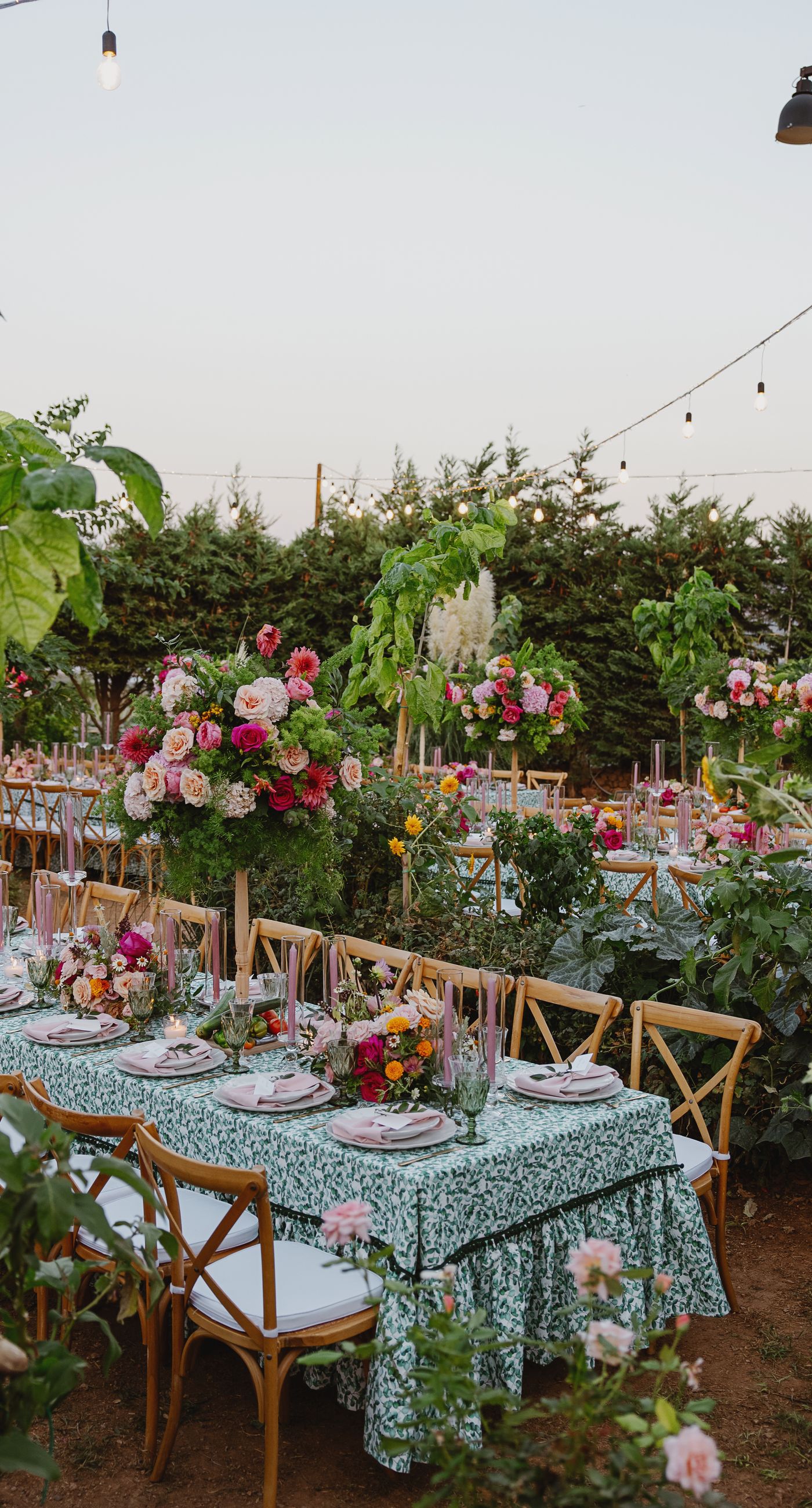 Where Celebration Meets Nature - A modern garden wedding with clean lines and a strong sense of a curated dining experience.
Long communal tables set within the vineyard, statement floral arrangements at varying heights, layers of greenery with bold color accents, and warm lighting that carried the atmosphere from day into night. A setting that felt natural yet intentionally designed  contemporary, vibrant, and effortlessly elegant. - Photo 2