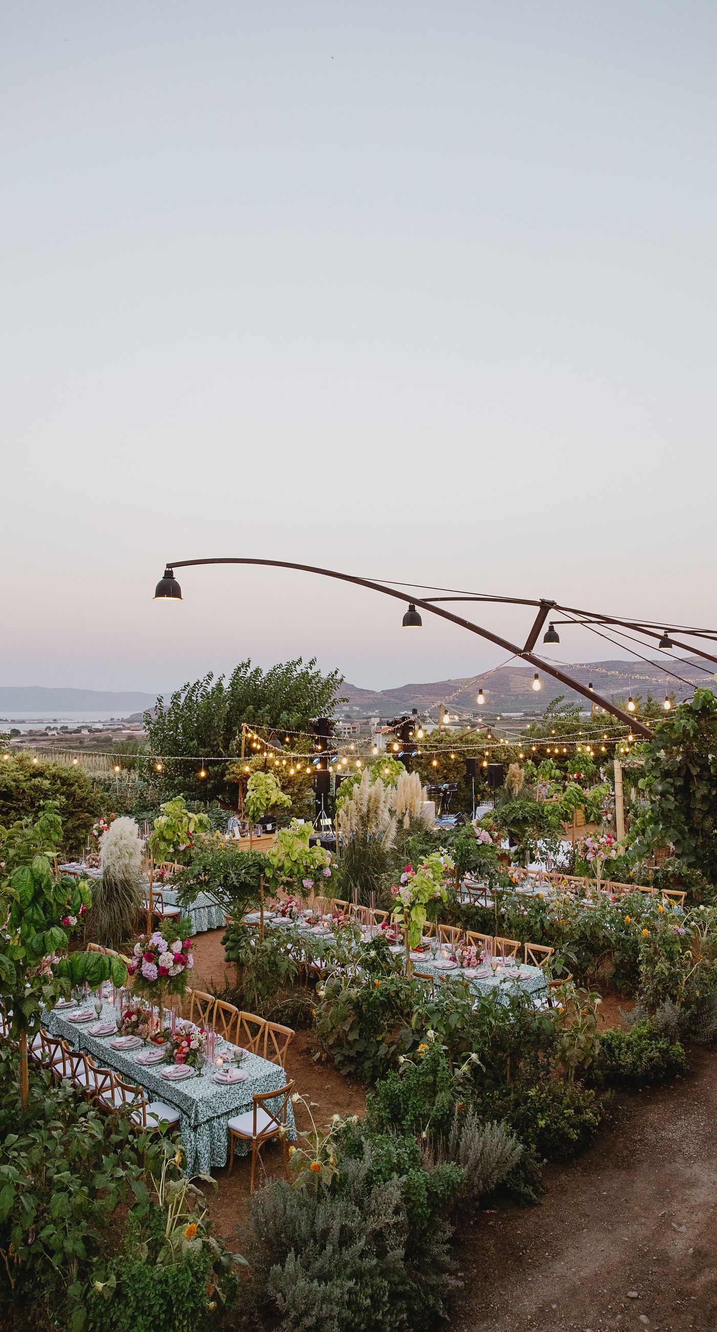 Where Celebration Meets Nature - A modern garden wedding with clean lines and a strong sense of a curated dining experience.
Long communal tables set within the vineyard, statement floral arrangements at varying heights, layers of greenery with bold color accents, and warm lighting that carried the atmosphere from day into night. A setting that felt natural yet intentionally designed  contemporary, vibrant, and effortlessly elegant. - Photo 1