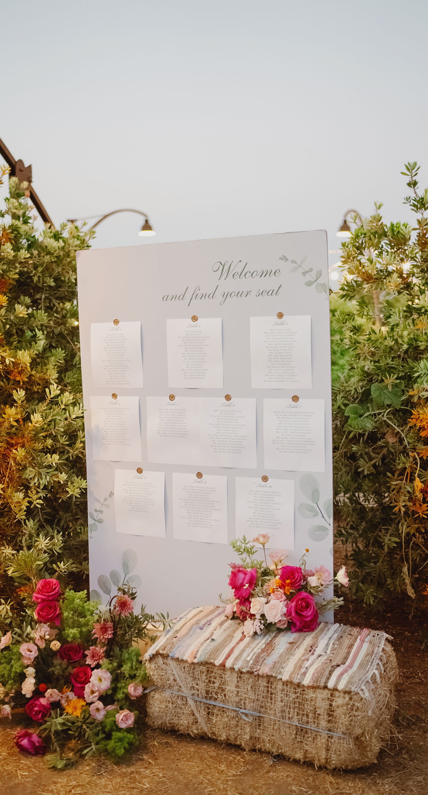 Where Celebration Meets Nature - A modern garden wedding with clean lines and a strong sense of a curated dining experience.
Long communal tables set within the vineyard, statement floral arrangements at varying heights, layers of greenery with bold color accents, and warm lighting that carried the atmosphere from day into night. A setting that felt natural yet intentionally designed  contemporary, vibrant, and effortlessly elegant. - Photo 10