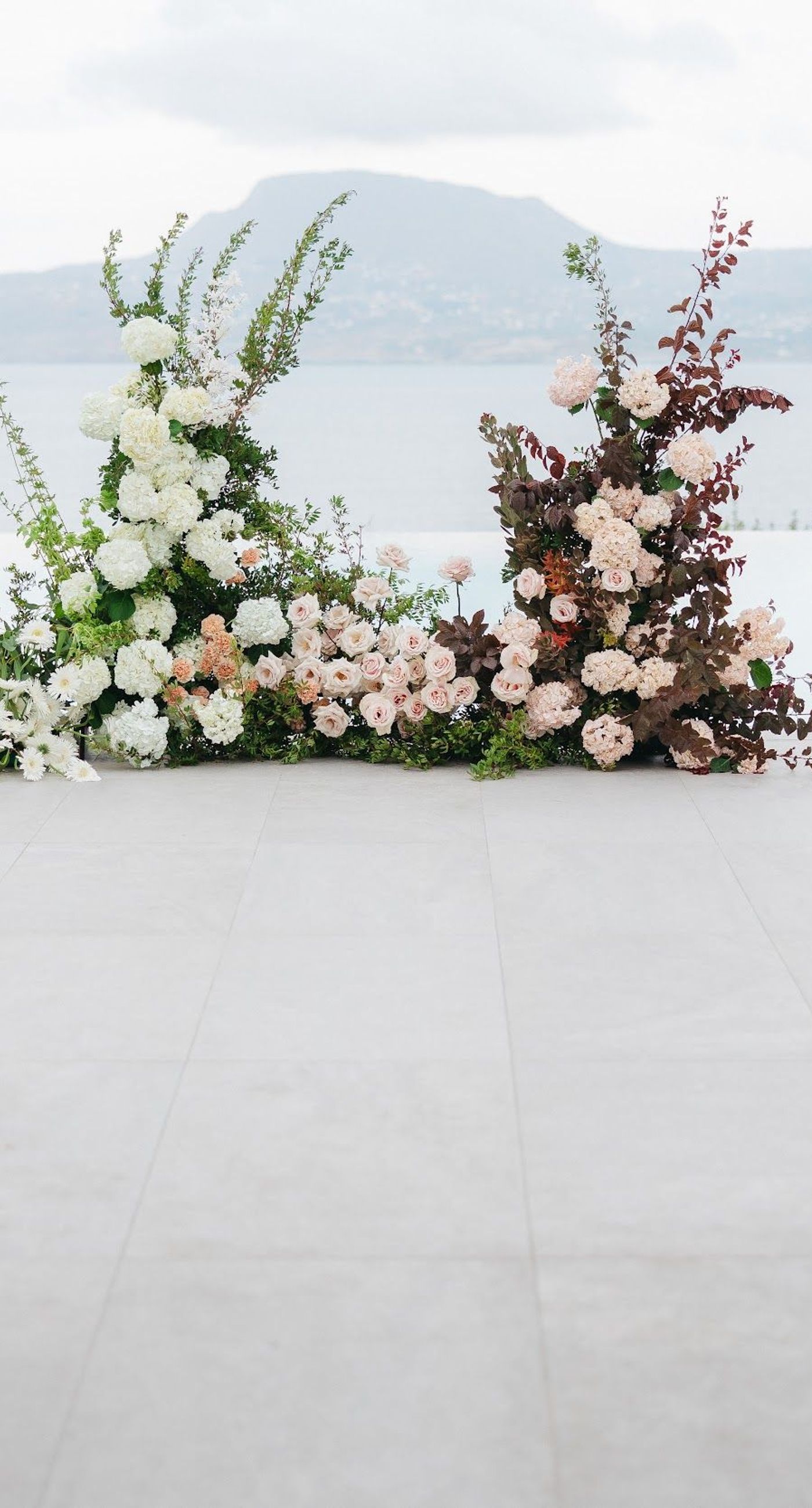 Shay & Vedad - In the serene elegance of a Greek wedding, a mirrored sign stands as a testament to love and artistry. The names "Shay and Vedad" are embossed in sleek white typography, reflecting a moment of intimate celebration bathed in soft, natural light. The minimalist, contemporary aesthetic is accented by subtle greenery, evoking a sense of tranquility and romance amidst the timeless beauty of Crete. The composition captures the harmonious blend of modern elegance with organic details, drawing you into a world where love and nature seamlessly intertwine. - Photo 1