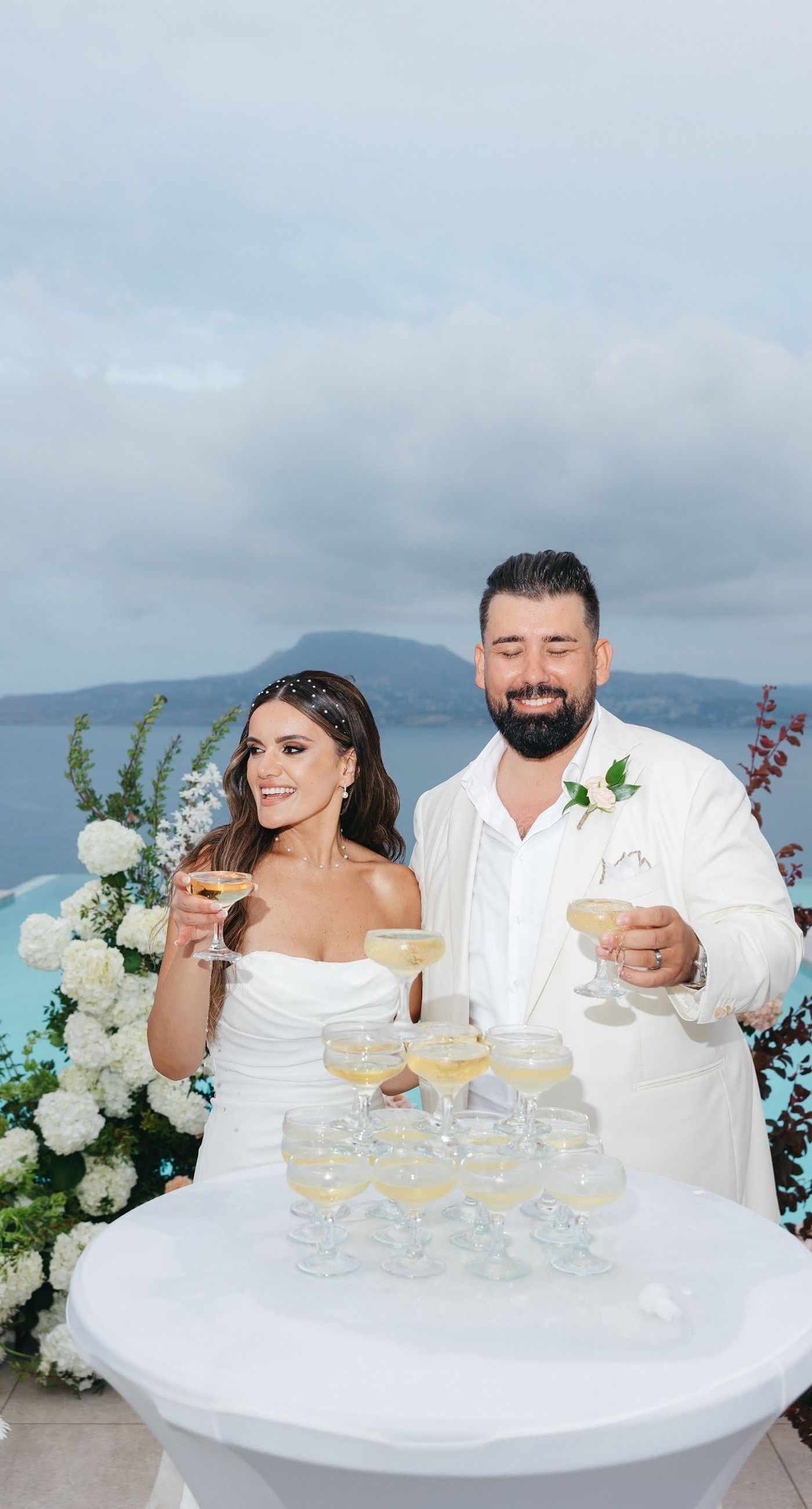 Shay & Vedad - In the serene elegance of a Greek wedding, a mirrored sign stands as a testament to love and artistry. The names "Shay and Vedad" are embossed in sleek white typography, reflecting a moment of intimate celebration bathed in soft, natural light. The minimalist, contemporary aesthetic is accented by subtle greenery, evoking a sense of tranquility and romance amidst the timeless beauty of Crete. The composition captures the harmonious blend of modern elegance with organic details, drawing you into a world where love and nature seamlessly intertwine. - Photo 6