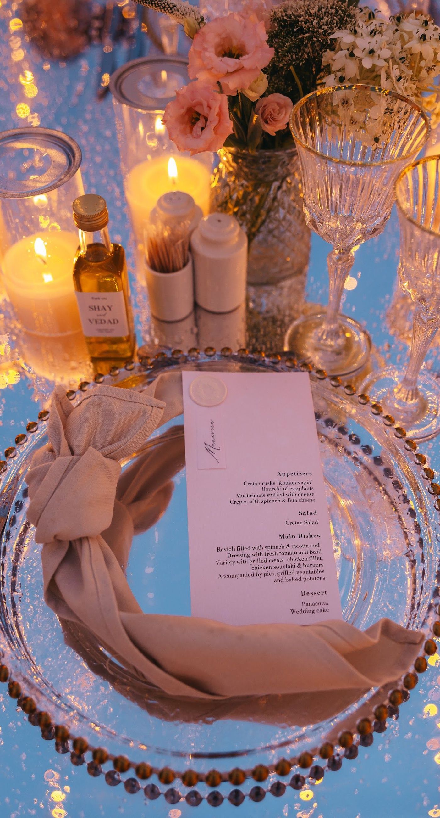 Shay & Vedad - In the serene elegance of a Greek wedding, a mirrored sign stands as a testament to love and artistry. The names "Shay and Vedad" are embossed in sleek white typography, reflecting a moment of intimate celebration bathed in soft, natural light. The minimalist, contemporary aesthetic is accented by subtle greenery, evoking a sense of tranquility and romance amidst the timeless beauty of Crete. The composition captures the harmonious blend of modern elegance with organic details, drawing you into a world where love and nature seamlessly intertwine. - Photo 9