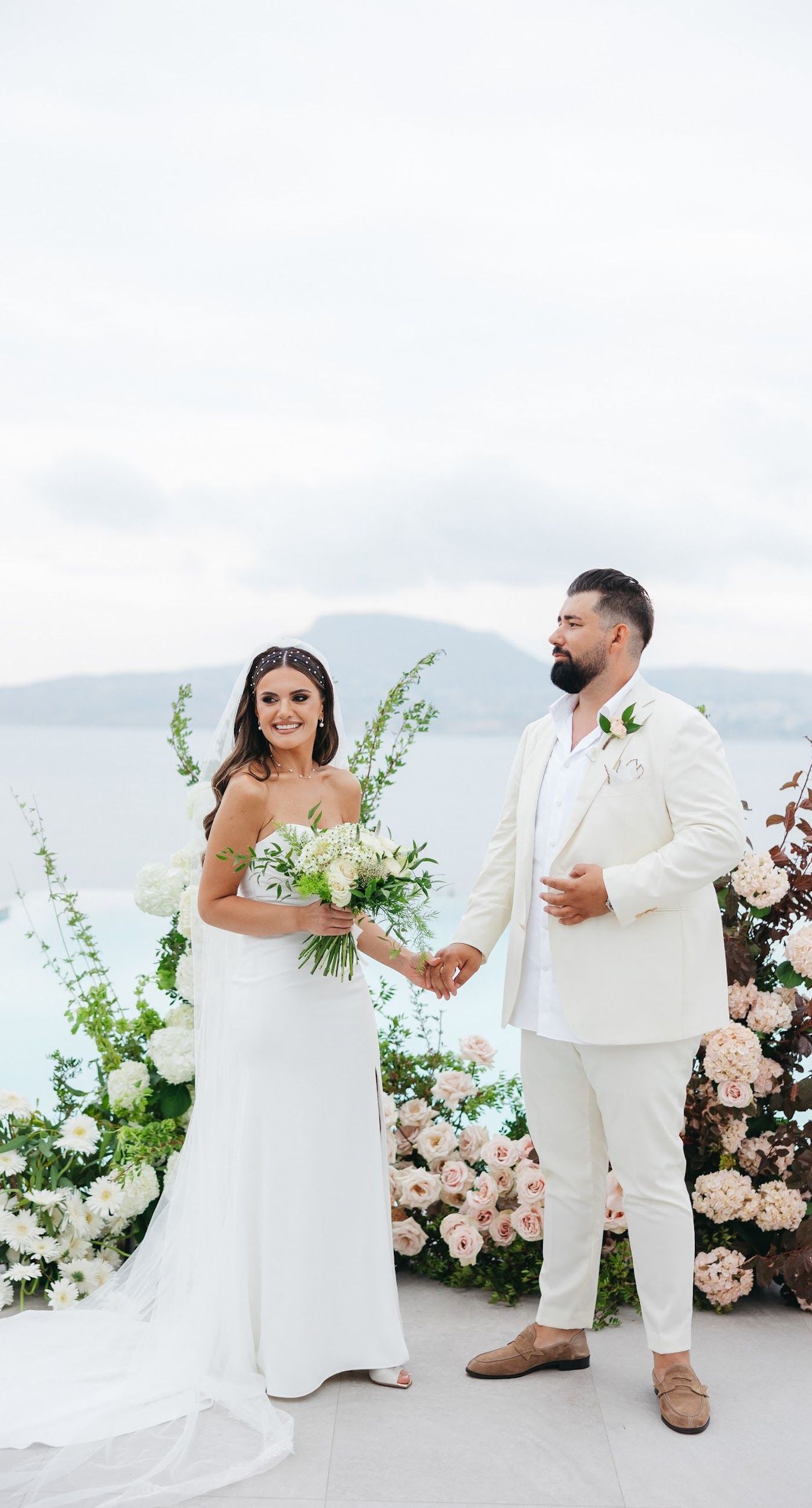 Shay & Vedad - In the serene elegance of a Greek wedding, a mirrored sign stands as a testament to love and artistry. The names "Shay and Vedad" are embossed in sleek white typography, reflecting a moment of intimate celebration bathed in soft, natural light. The minimalist, contemporary aesthetic is accented by subtle greenery, evoking a sense of tranquility and romance amidst the timeless beauty of Crete. The composition captures the harmonious blend of modern elegance with organic details, drawing you into a world where love and nature seamlessly intertwine. - Photo 4