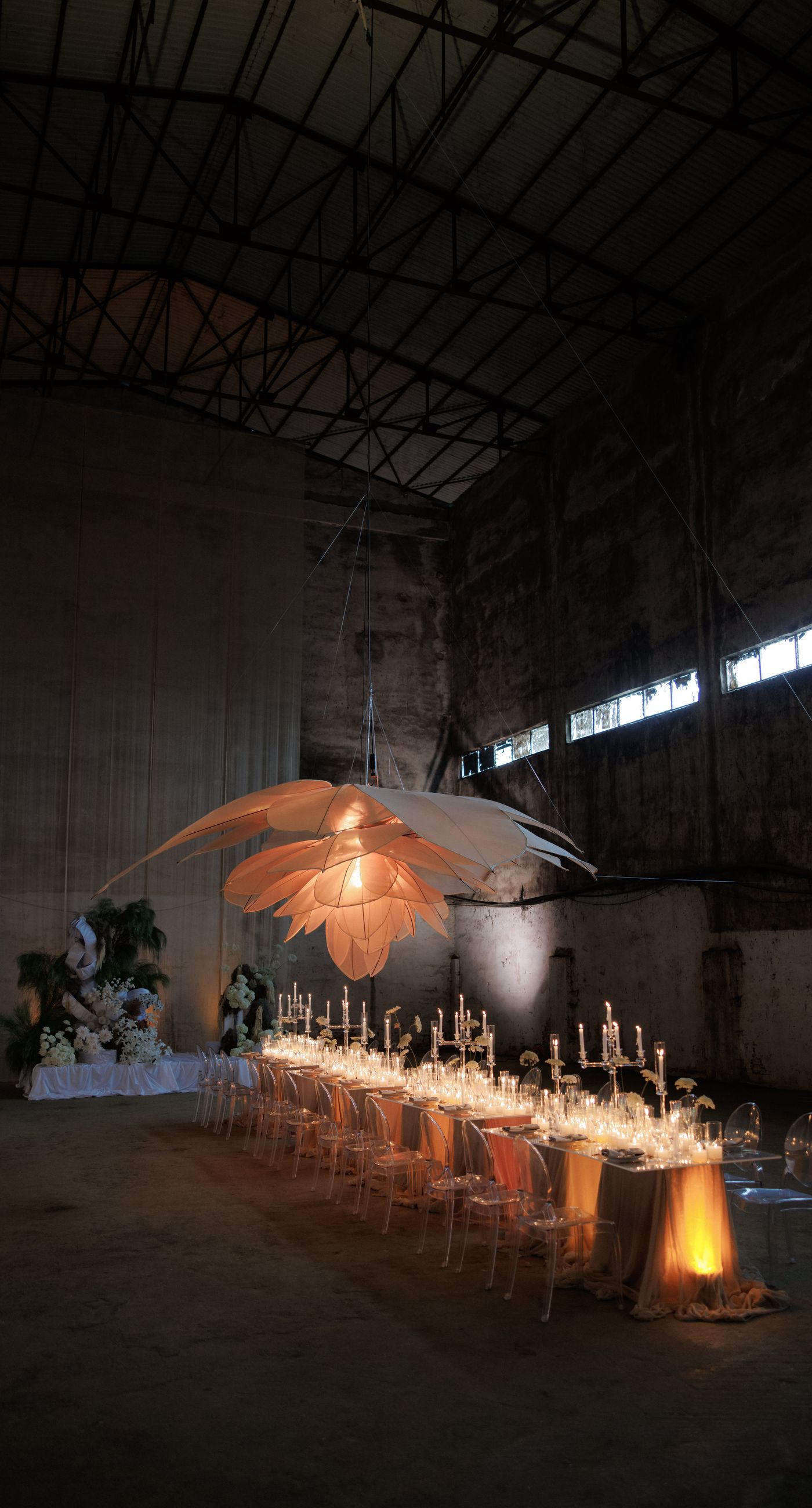 The Extravaganza Flower - Set within an industrial space, this project was conceived as an atmospheric dining experience where light and form take center stage. A sculptural, suspended installation “blooms” above the table, creating depth and scenography, while a candlelit setup adds warmth and intimacy. Clean lines, transparent materials, and subtle florals complete a design that goes beyond decoration it is installation art with emotion. - Photo 8